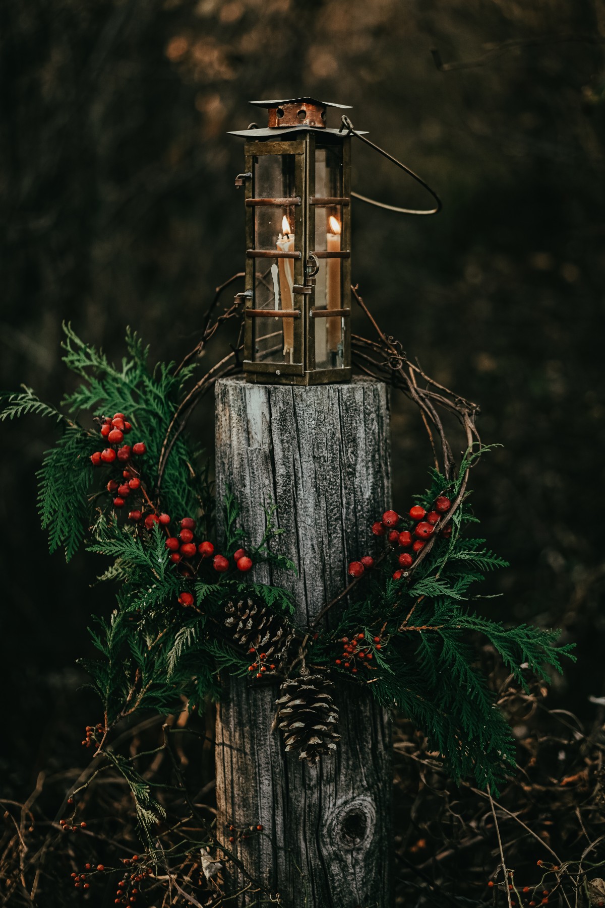 outdoor post decorated with a lantern and greenery