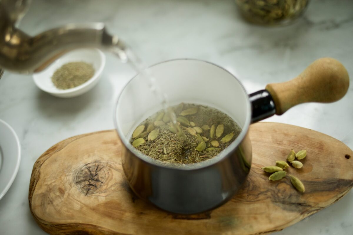 pouring hot water into a mug of herbs