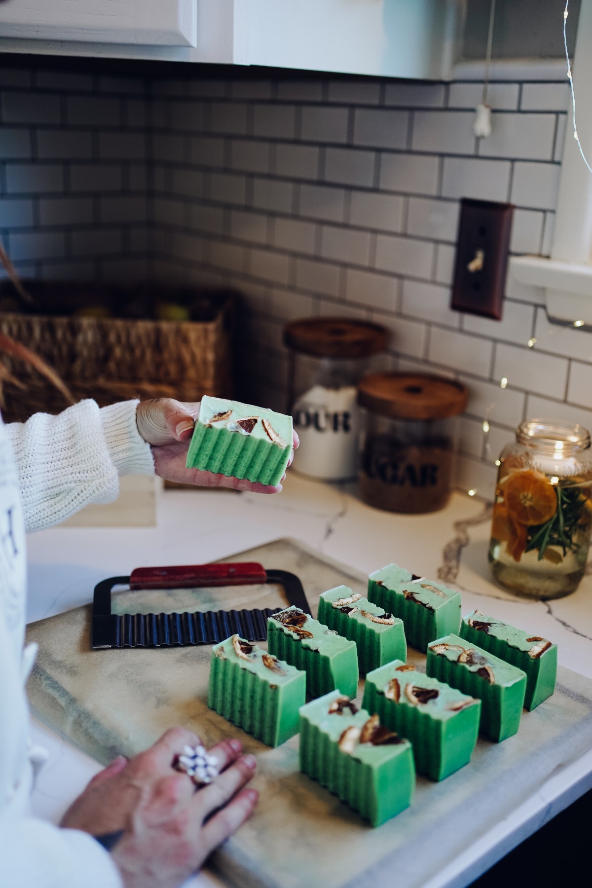 hand holding up holiday soap with soap on a cutting board