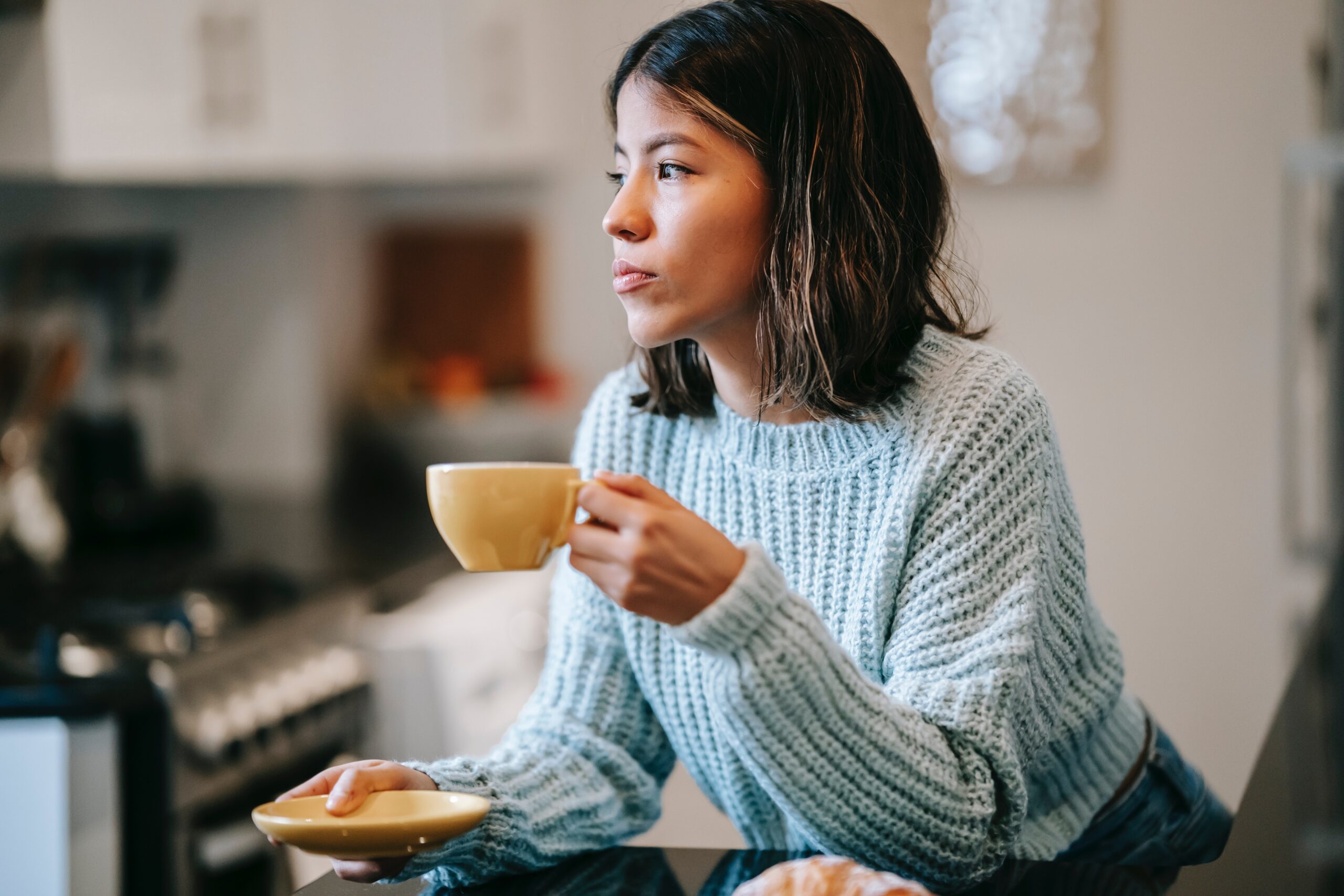 woman drinking a cup of tea and looking out a window