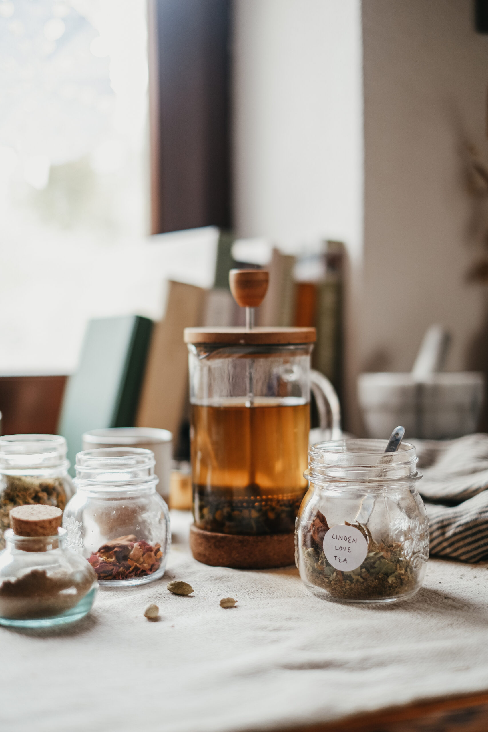 brewing Linden Love Tea in a french press with jars of dried herbs on a tablecloth