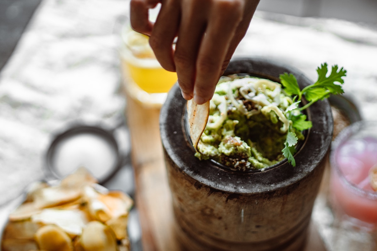 hand dipping a chip into a bowl of guacamole