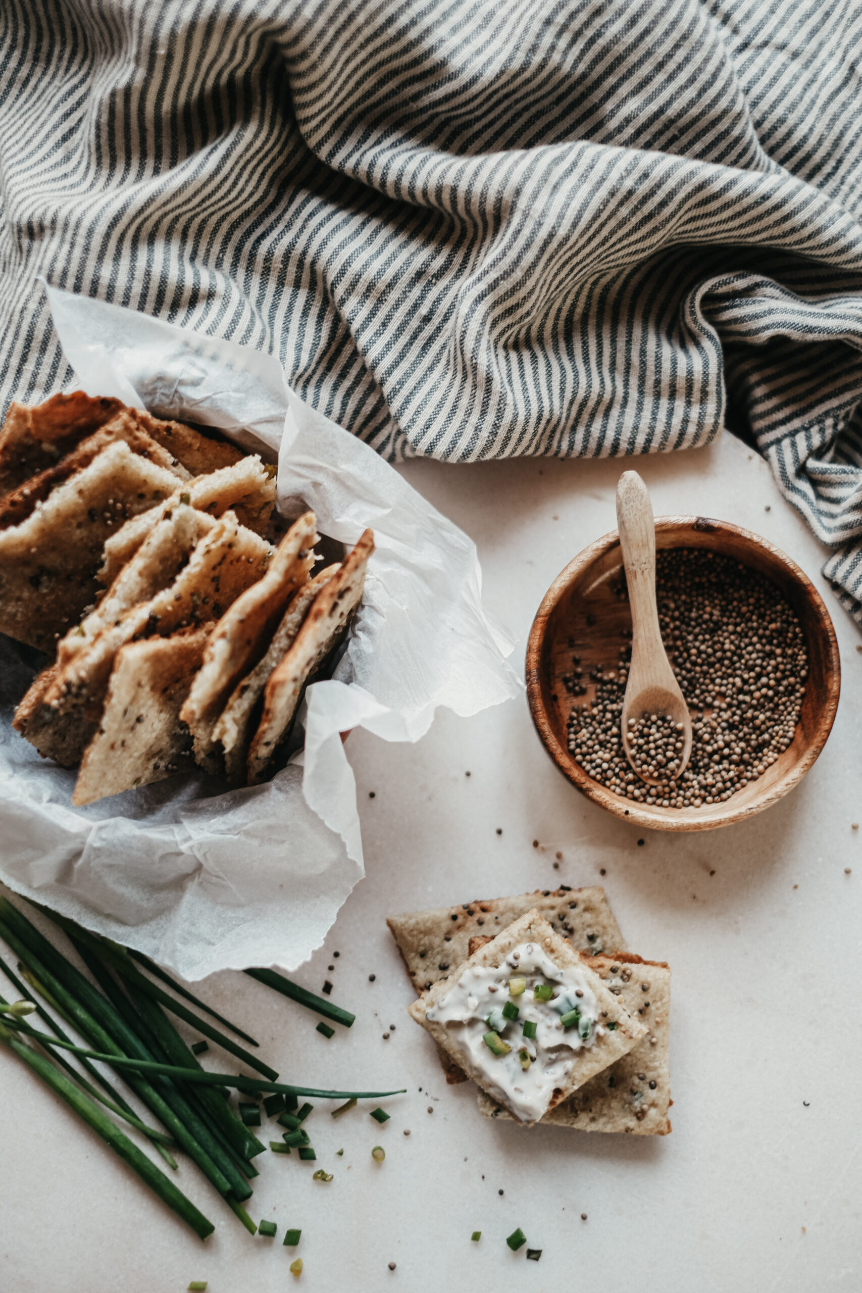 homemade crackers in a bowl and stacked on a table with a bowl of mustard seeds next to them