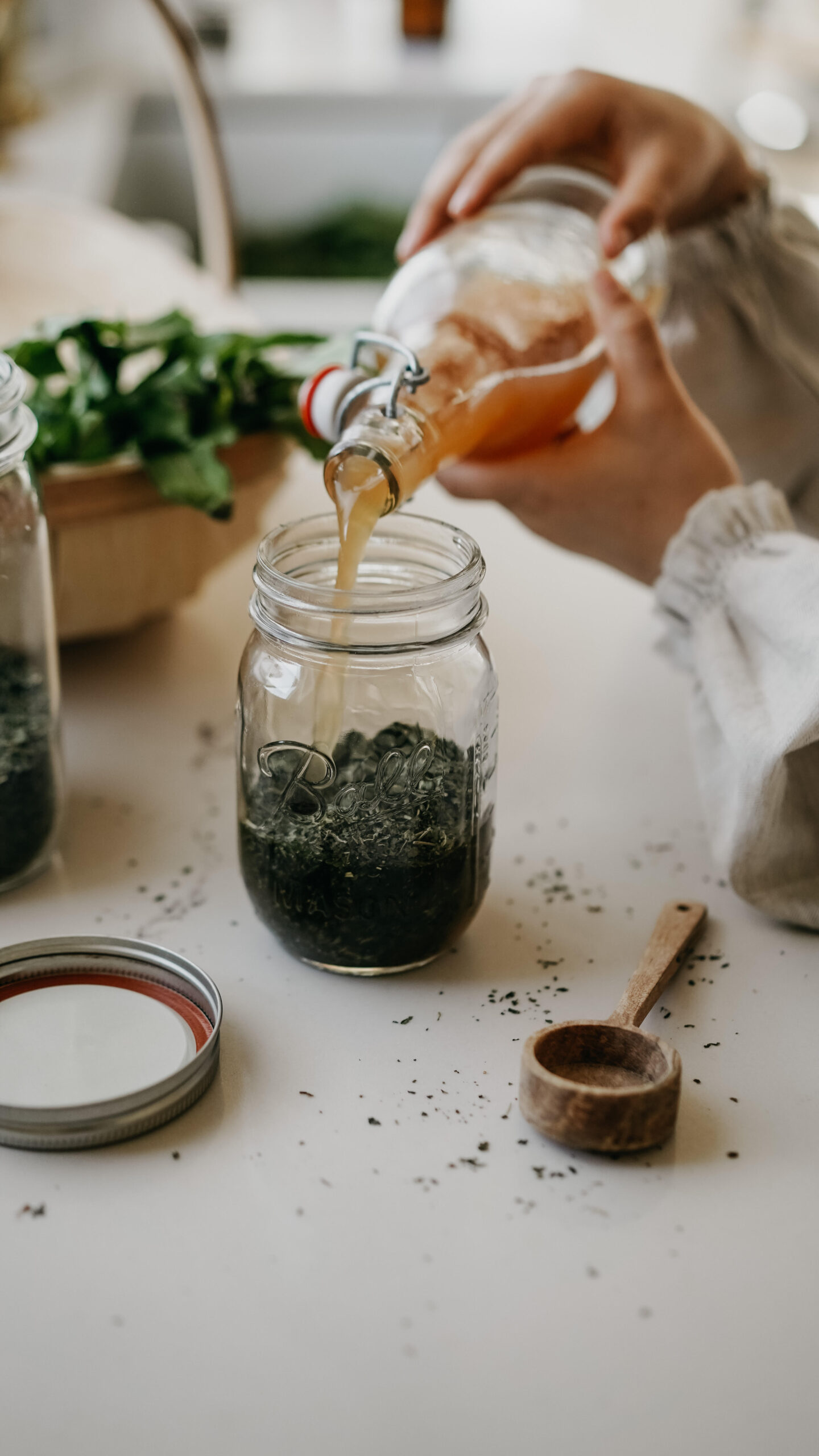 pouring vinegar into a jar of herbs for an oxymel recipe