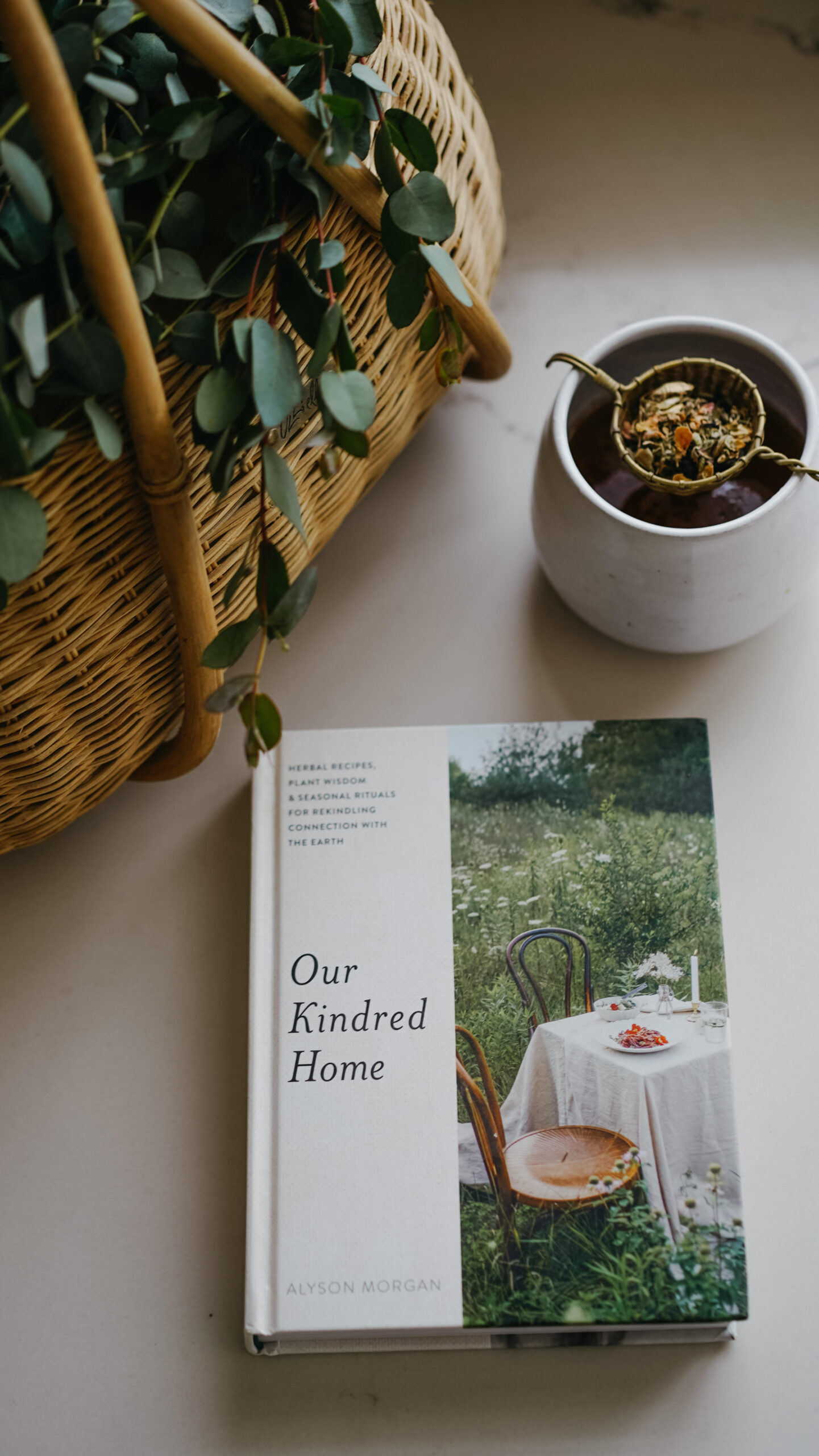 book on a table with basket and mug of straining tea