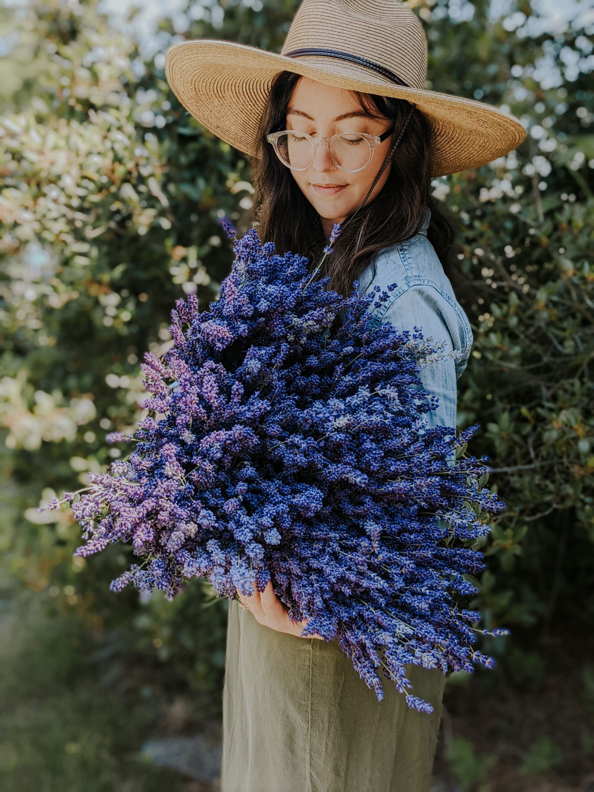woman looking down at an armful of lavender