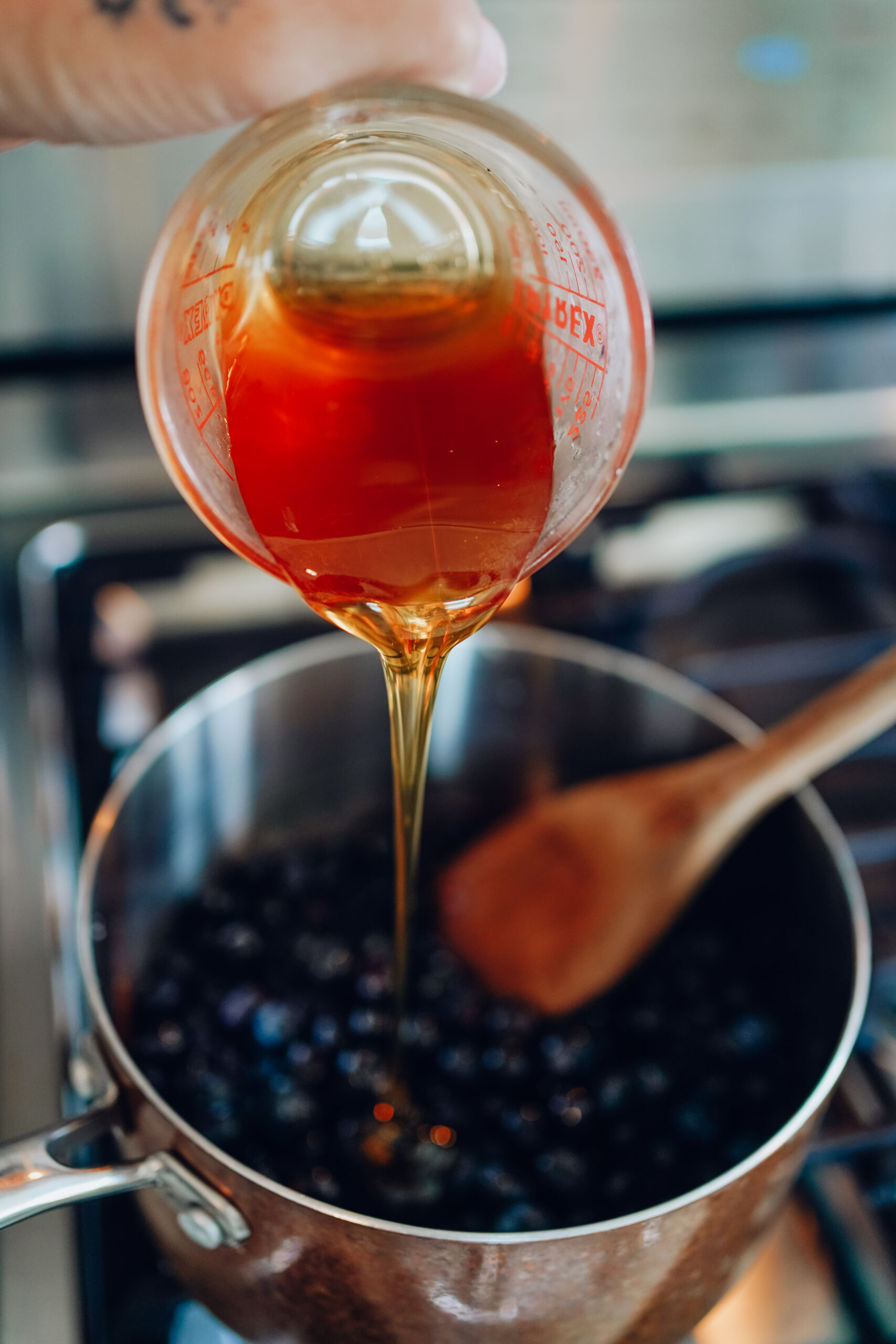 pouring honey into a pot of berries
