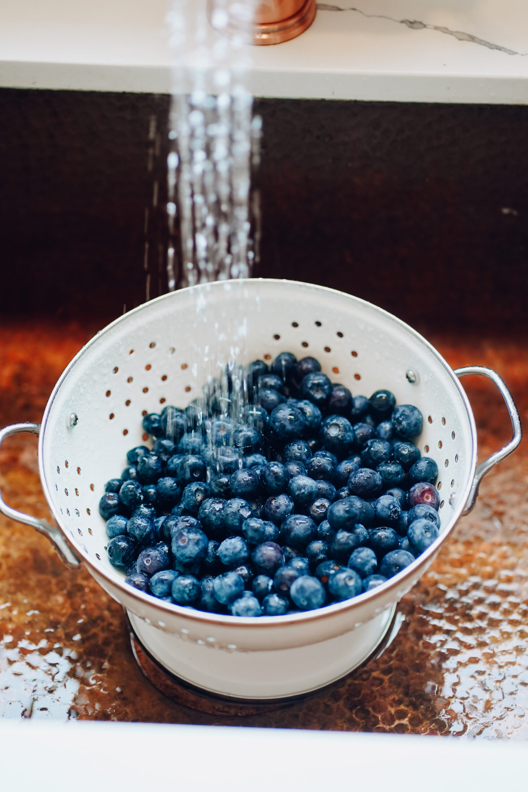 rinsing blueberries in a colander