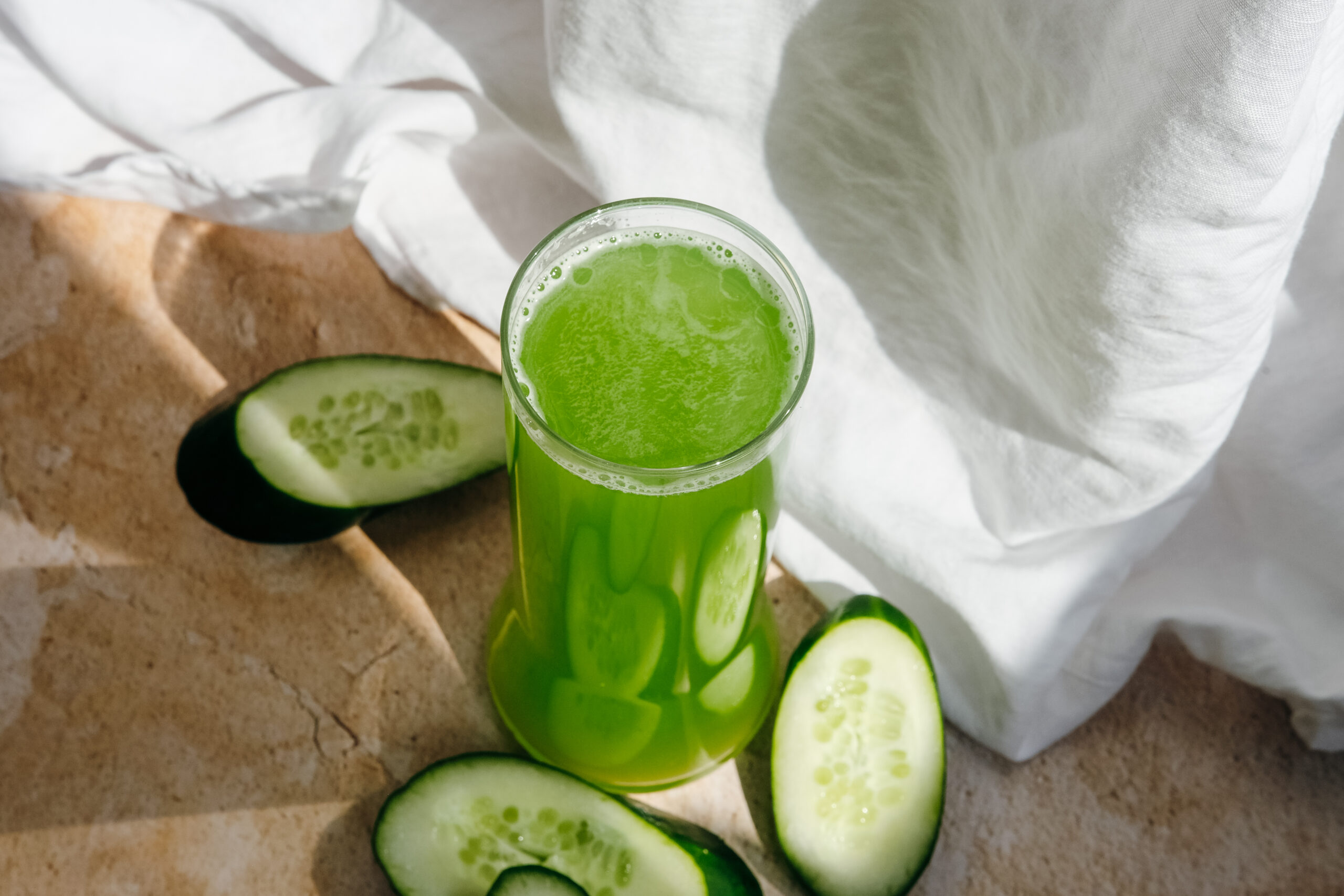 basil and thyme limeade in a glass with sliced cucumbers on the table