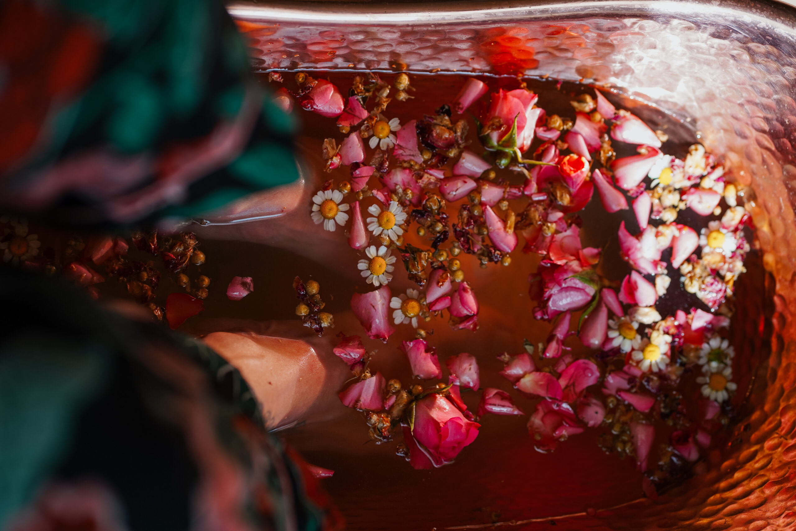 woman taking a foot bath soak with roses and chamomile