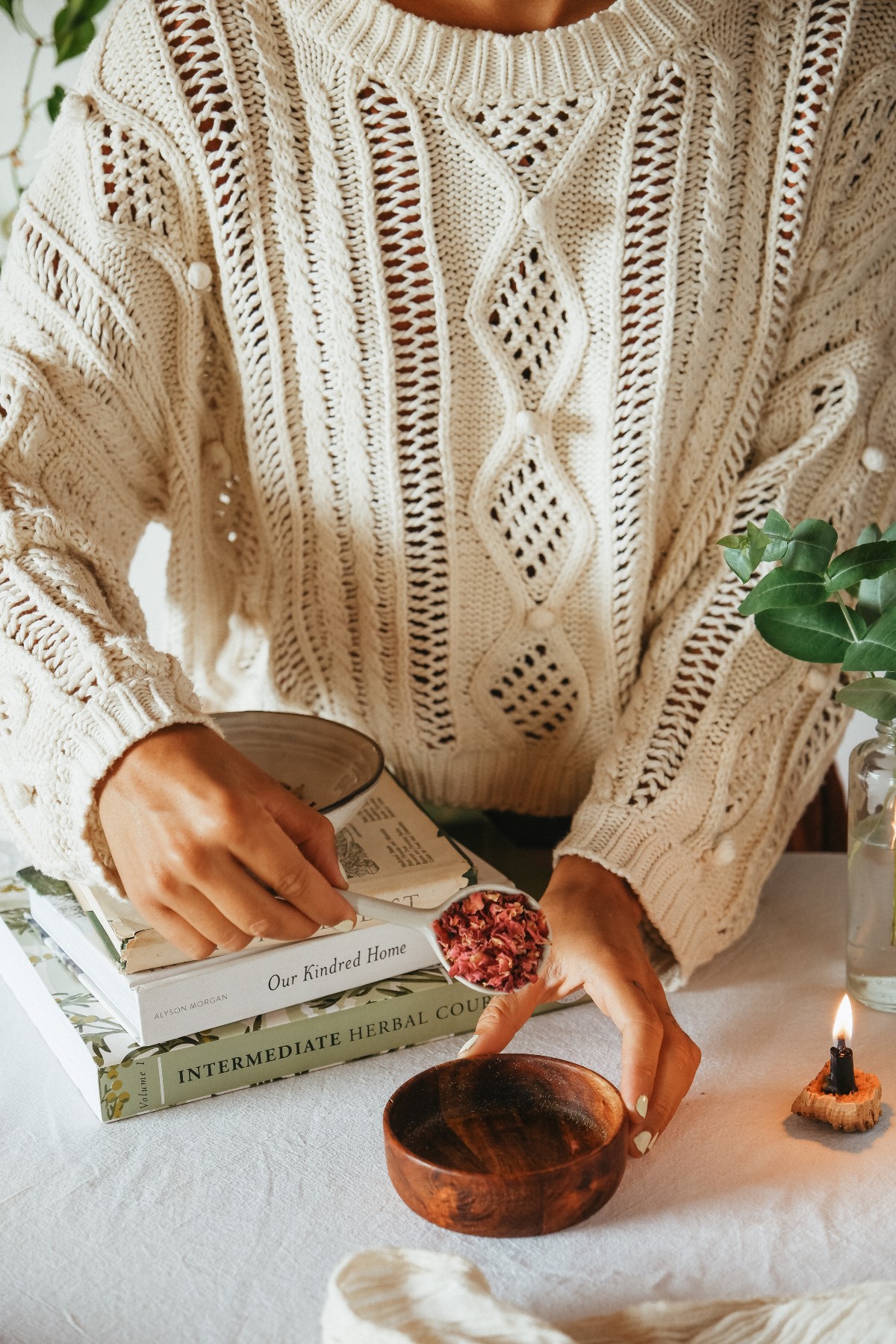 herbalist pouring dried rose petals in a wooden bowl