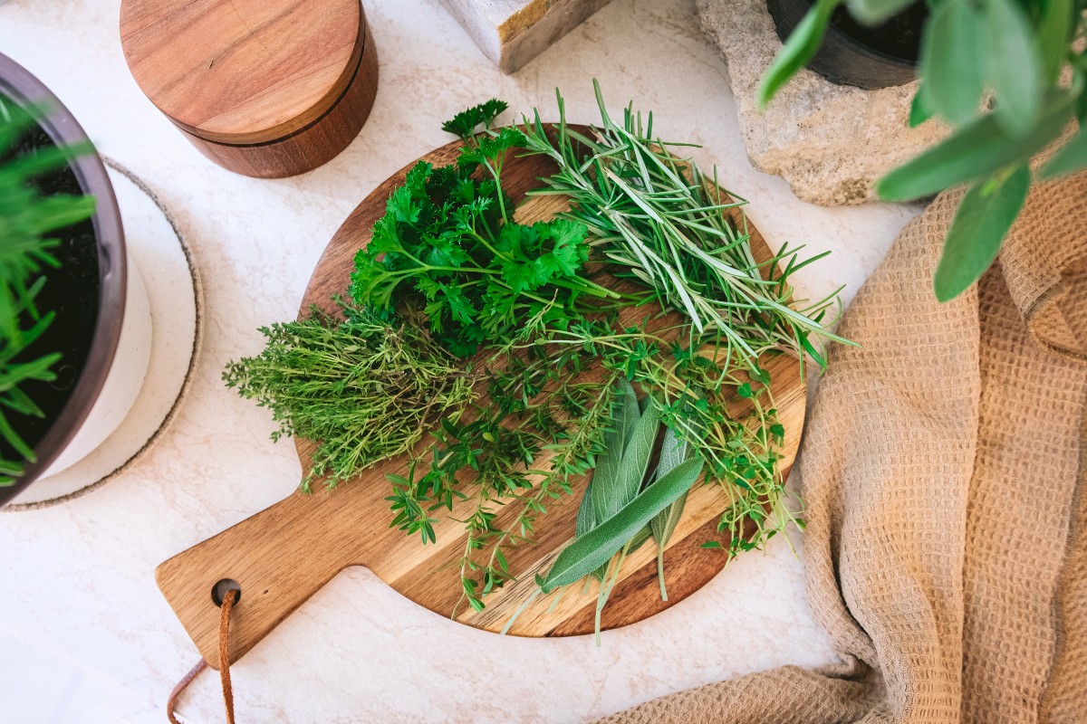 piles of herbs on a round wooden cutting board