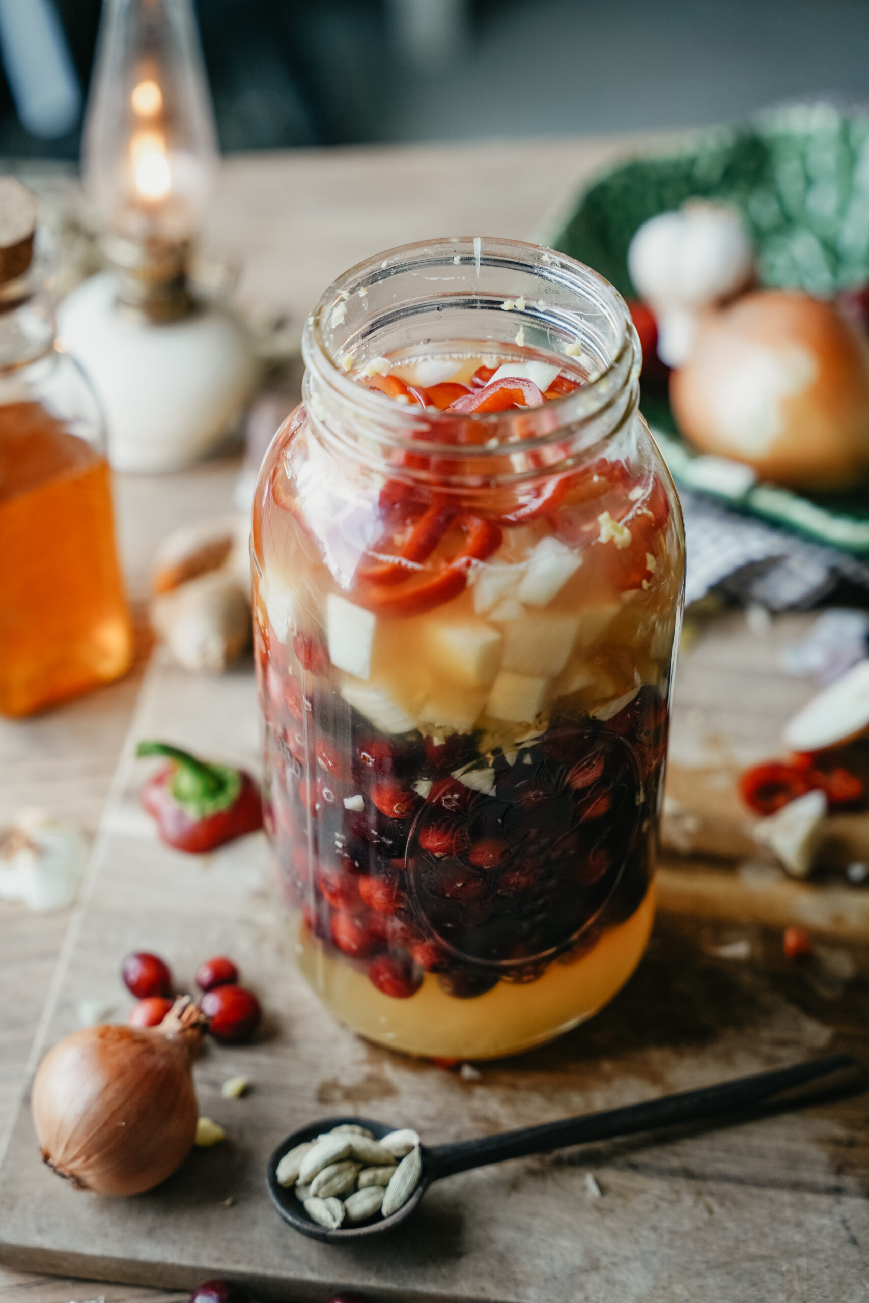 jar of fire cider with fire cider ingredients next to it on a cutting board