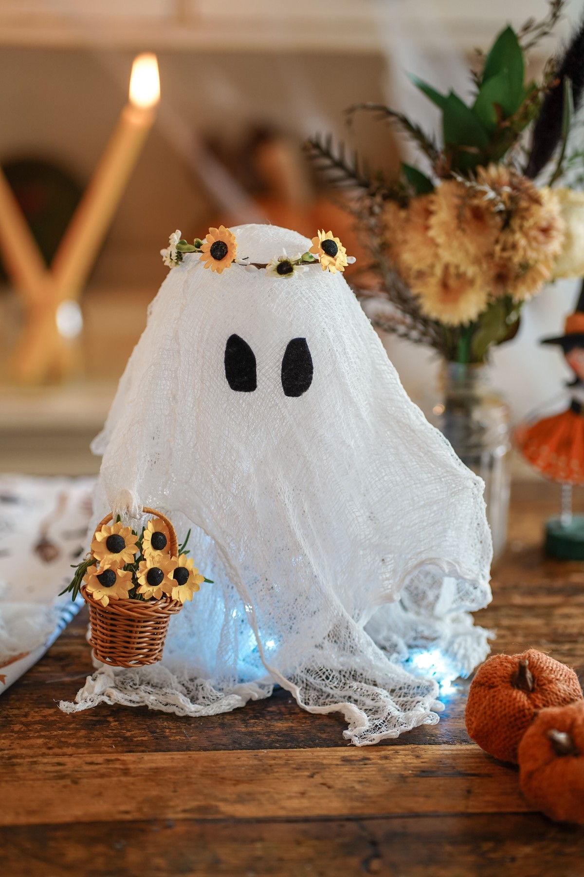 Halloween cheesecloth ghost standing on a table holding a basket of flowers