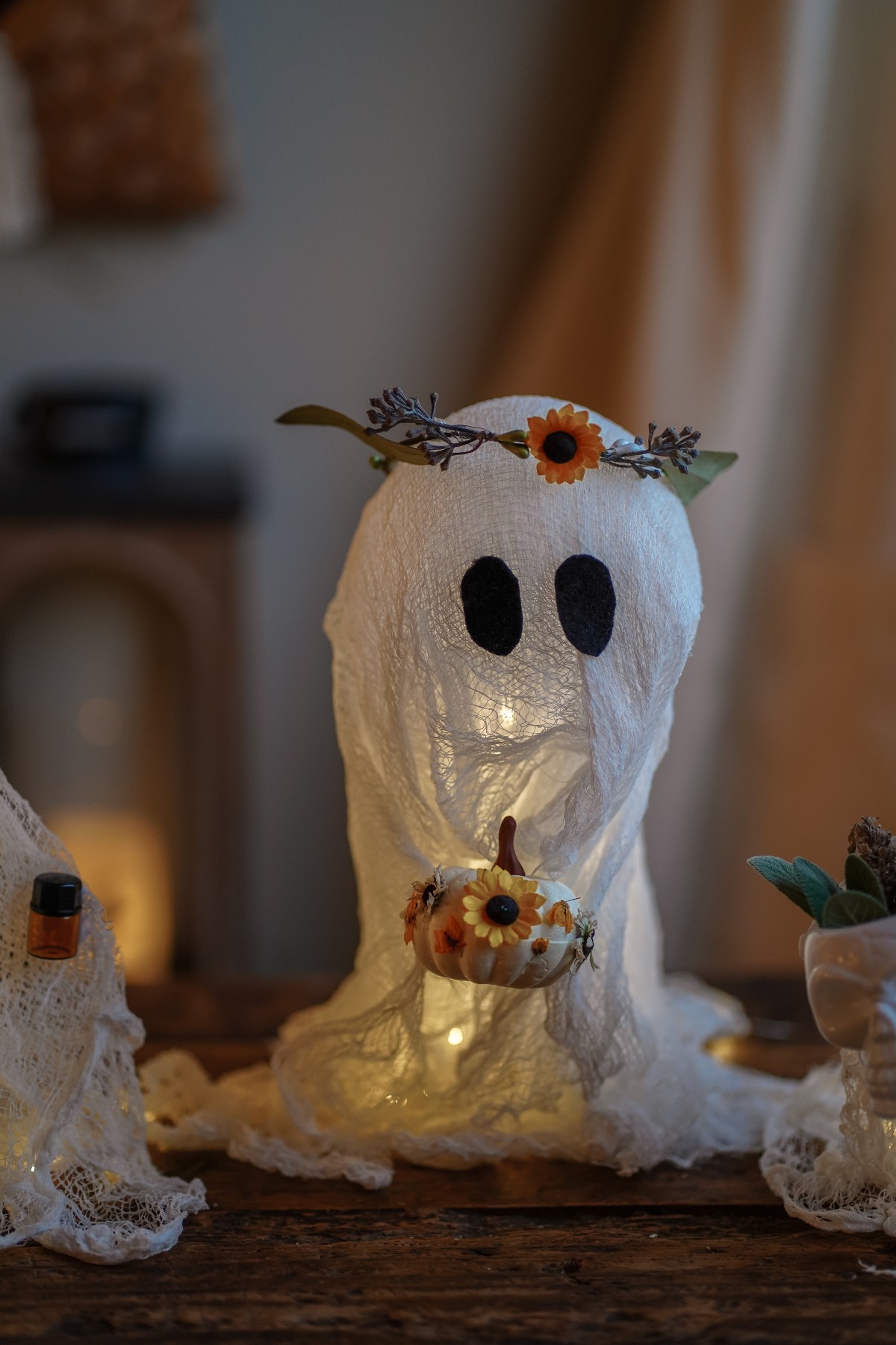 Halloween cheesecloth ghost holding a small pumpkin