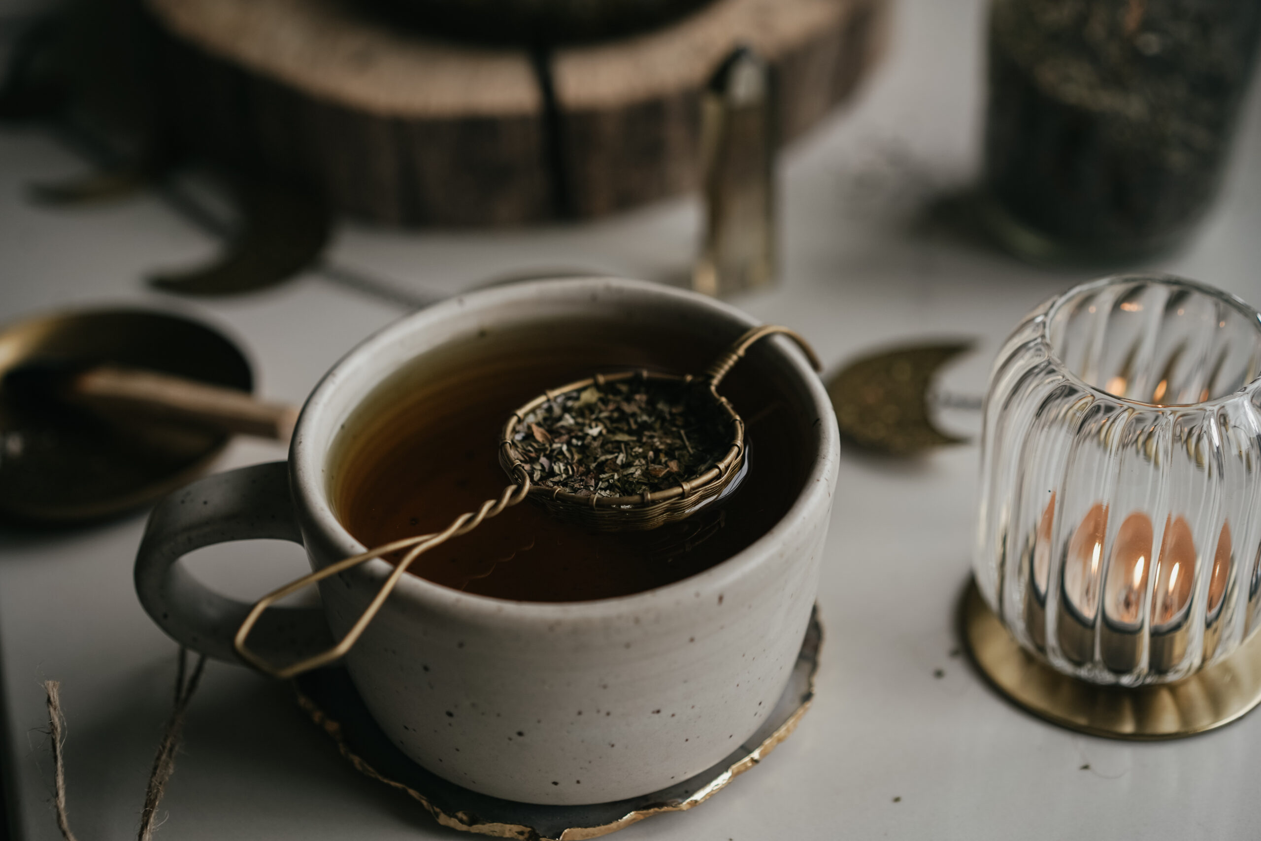 strainer of herbs sitting on top of a cup of infusion