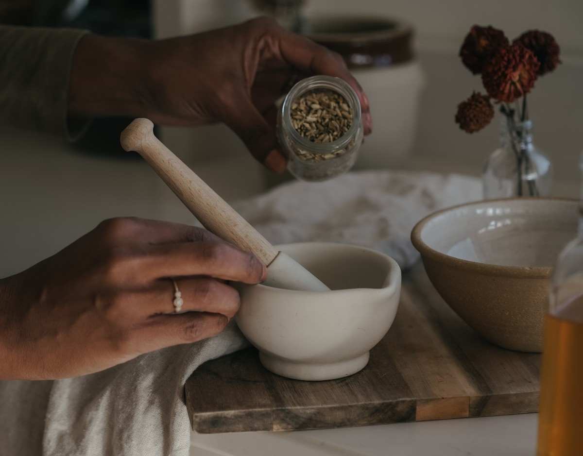 pouring herbs from a jar into a mortar and pestle