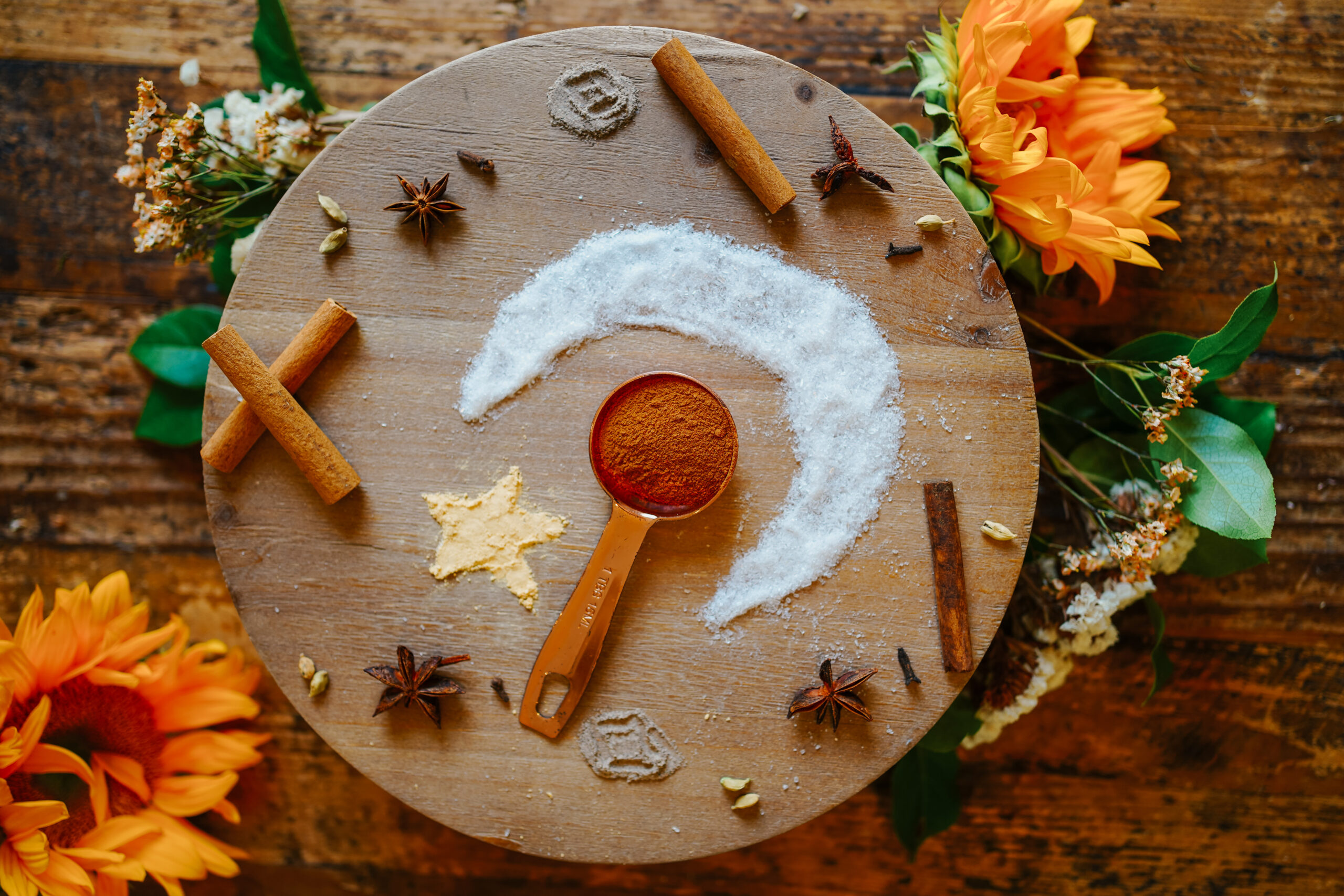 powdered cinnamon on a spoon on a wooden circle surrounded by herbs