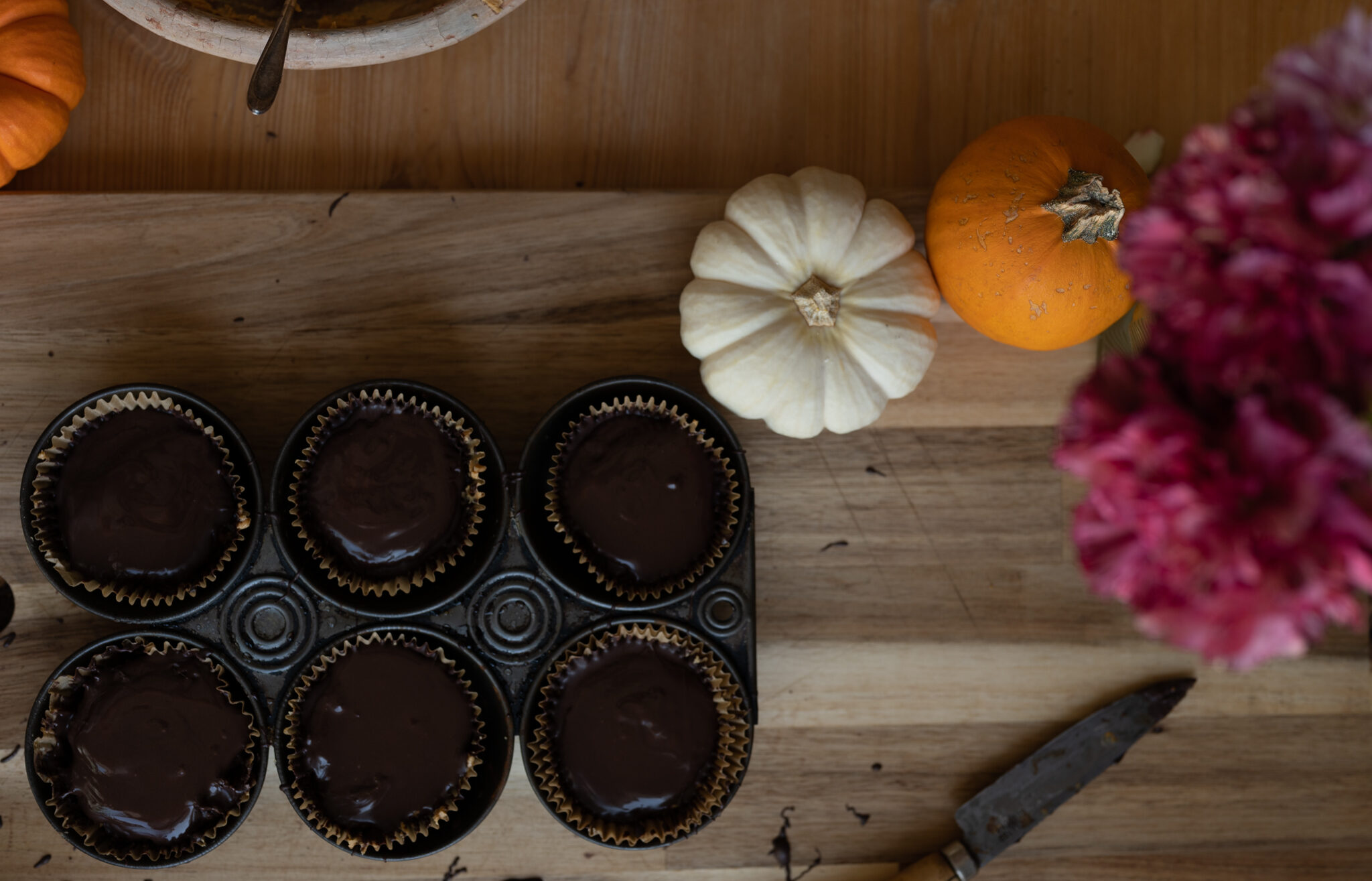 herbal peanut butter cups in a muffin pan with flowers and pumpkins next to it