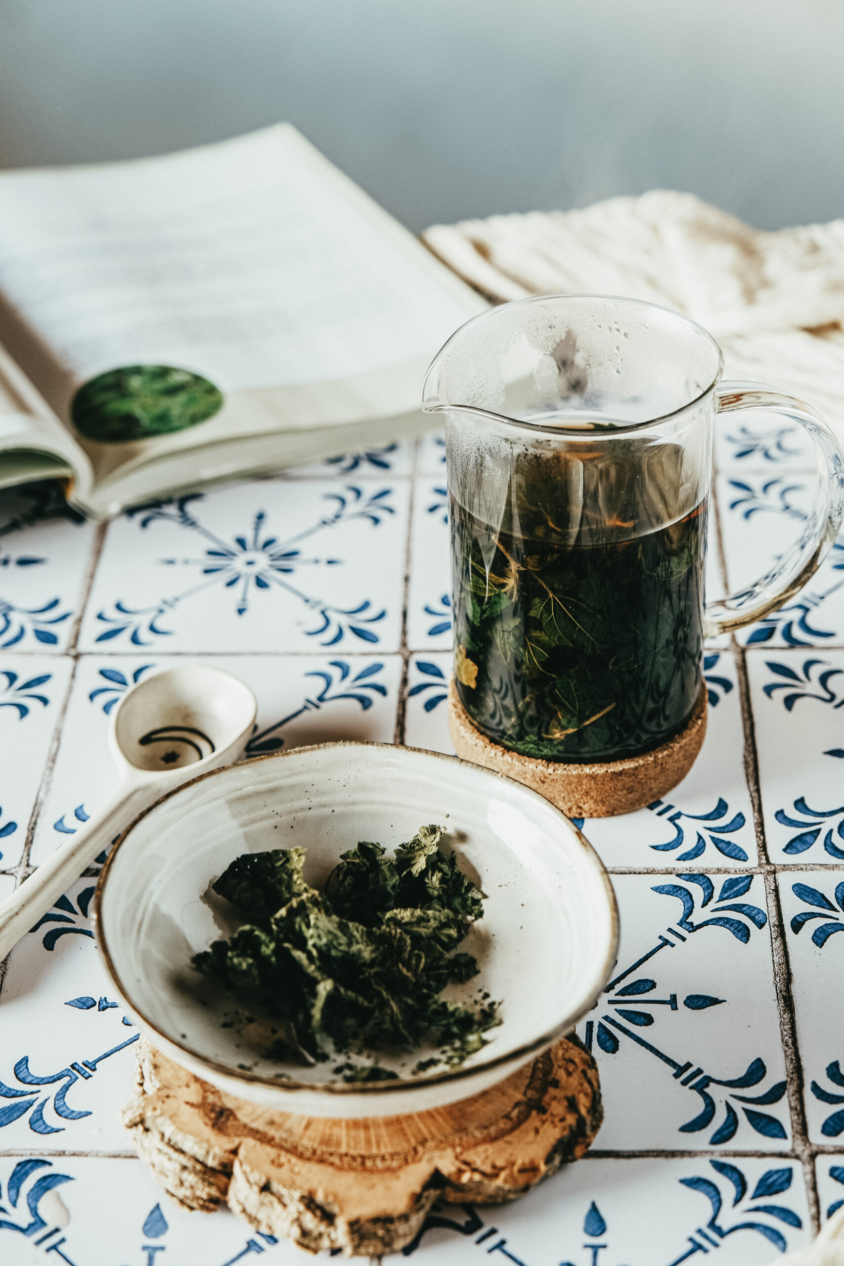 pot of nettle leaf tea with a bowl of nettle next to it