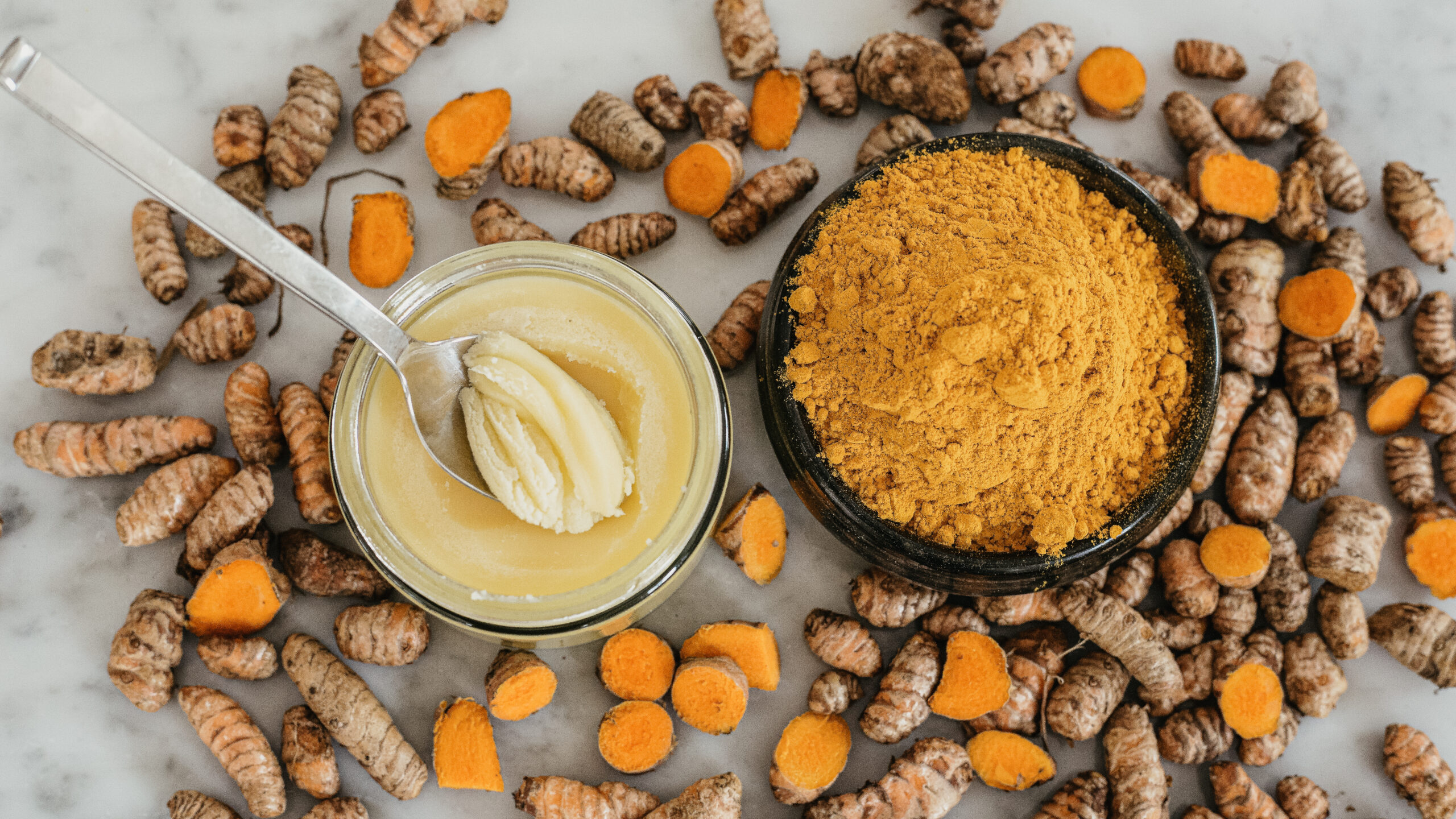 a bowl of ghee next to a bowl of turmeric