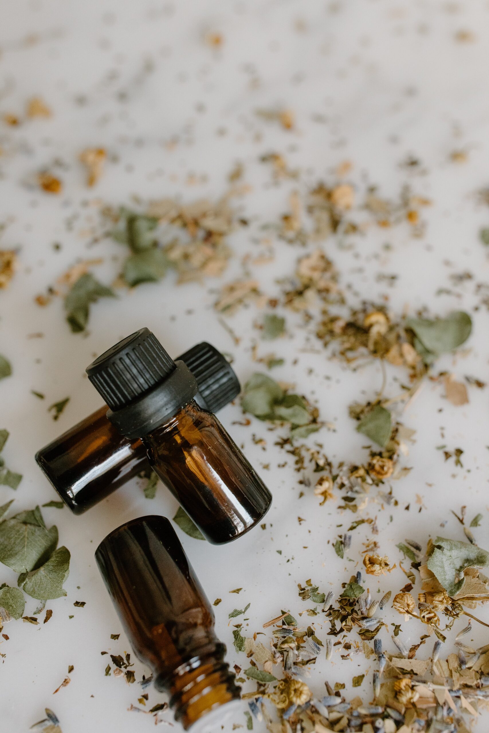 essential oil bottles with dried herbs loose on table