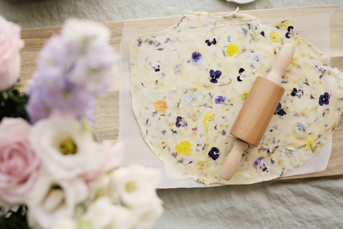 a rolling pin on top of pressed flower cracker dough