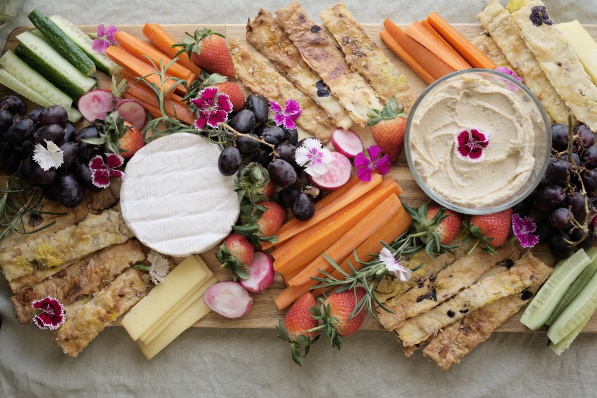 charcuterie board that includes a variety of foods including pressed flower crackers