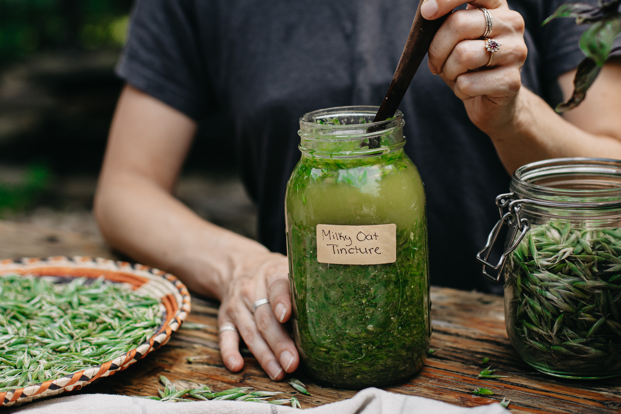 woman stirring a jar of milky oat tincture