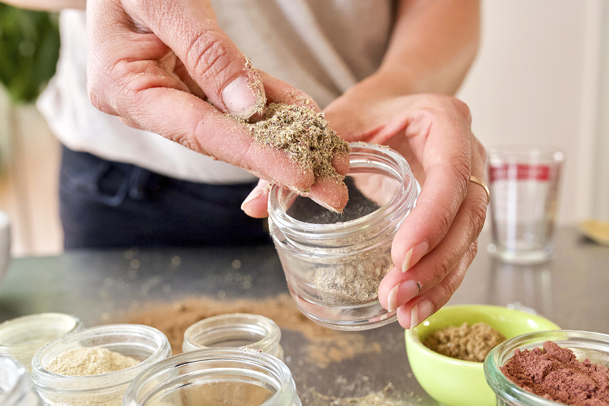 woman pulling powdered herbs from a jar