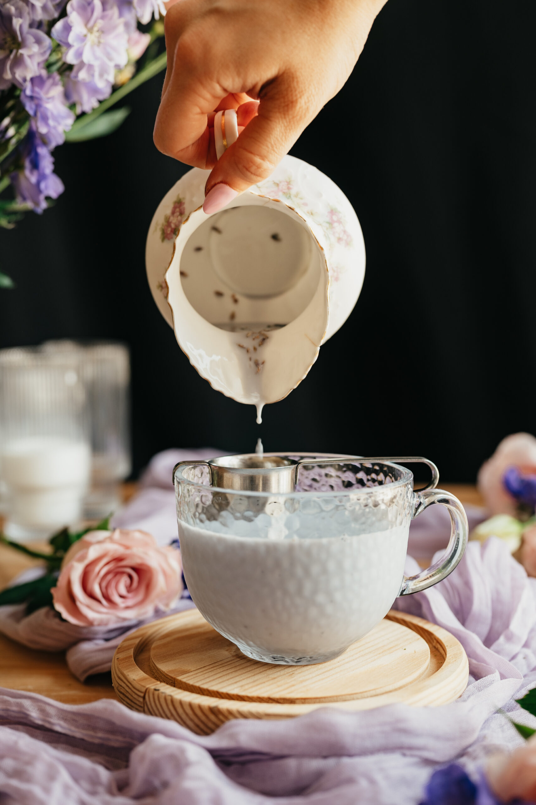 a pitcher pouring lavender matcha latte into a glass cup