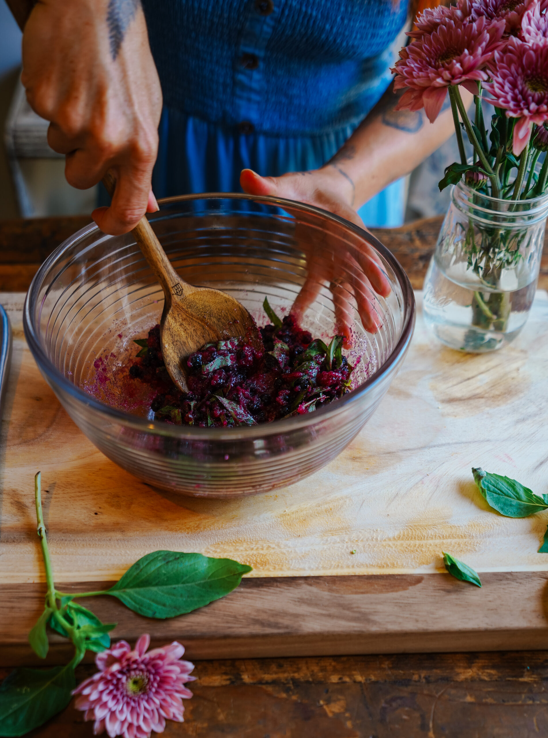 wooden spoon mashing blueberries in a glass bowl