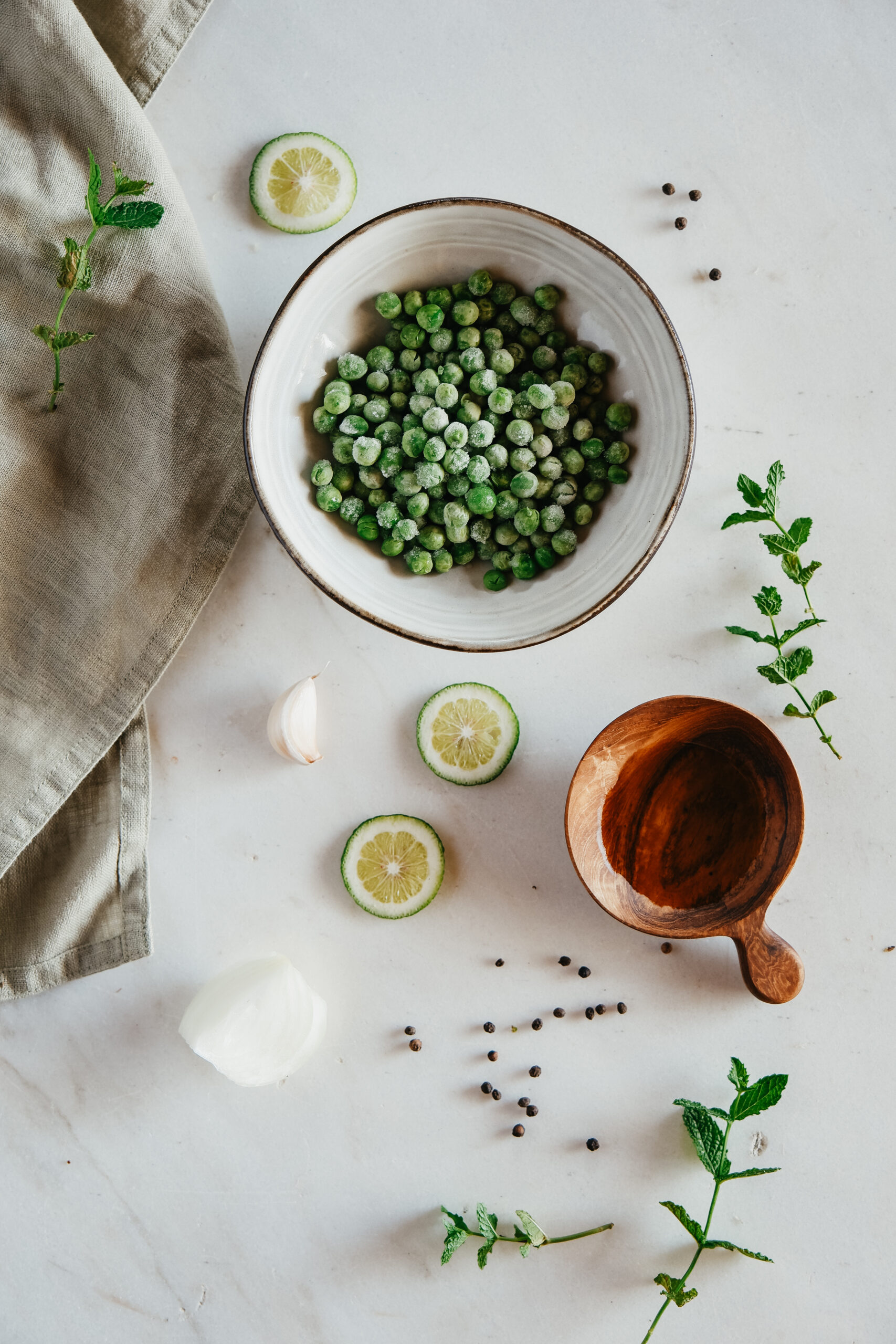 peas in a bowl with lime slices and herbs around on the table