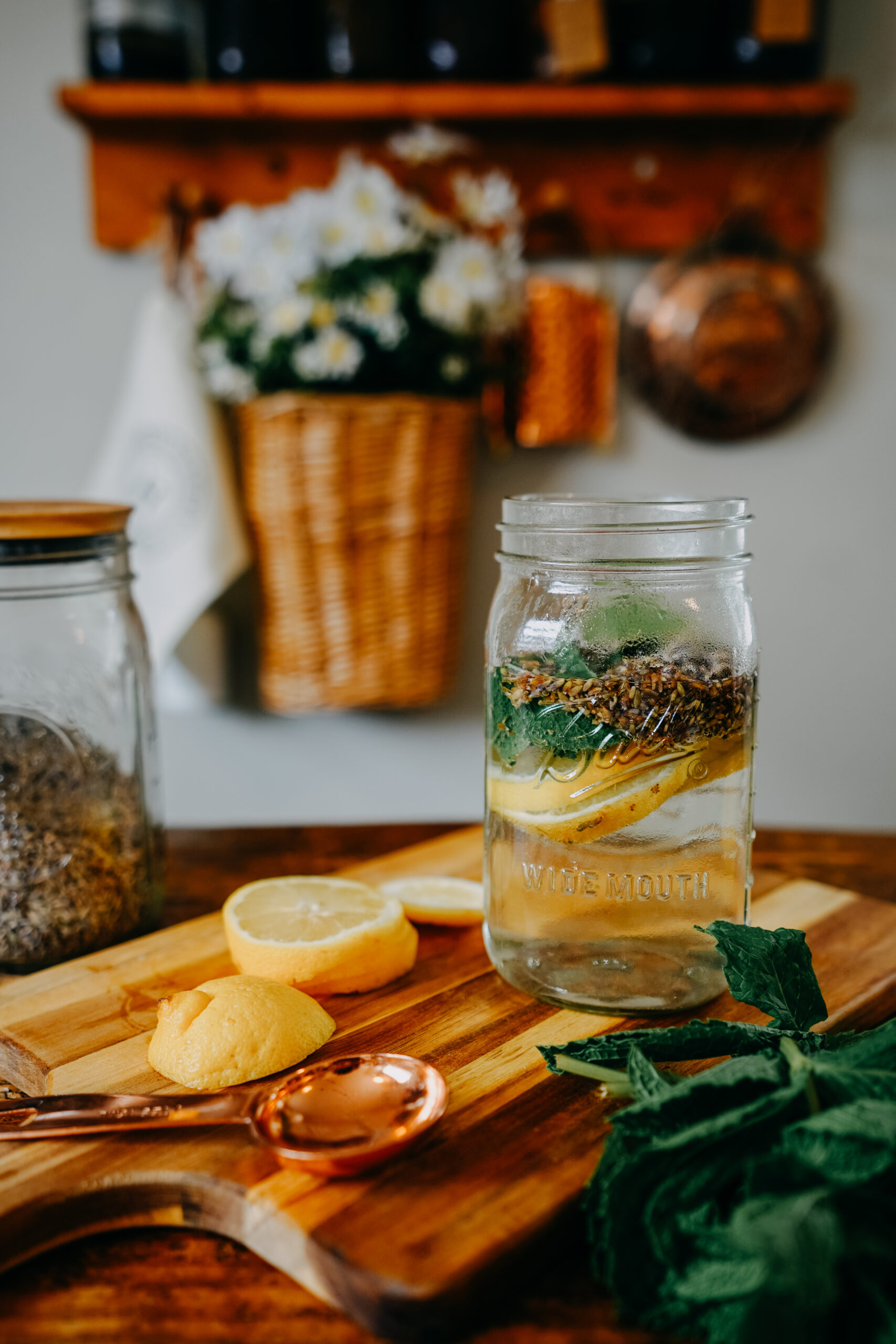 quart jar of water with lemon slices, lavender, and mint surrounded by lemon slices and herbs