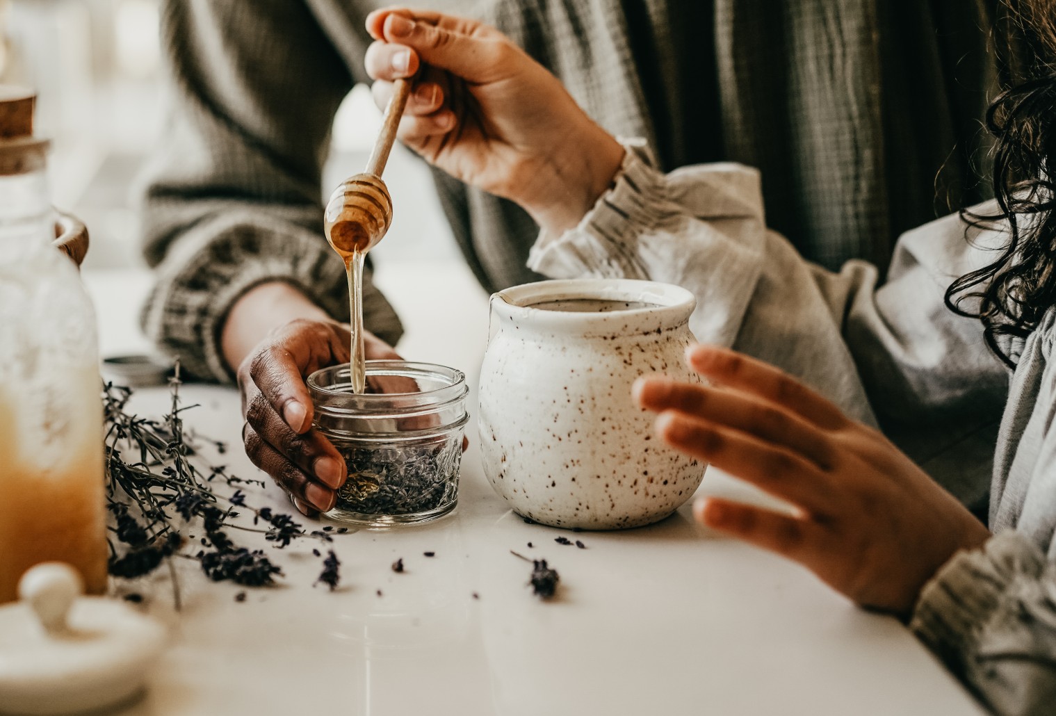 child drizzling honey over herbs