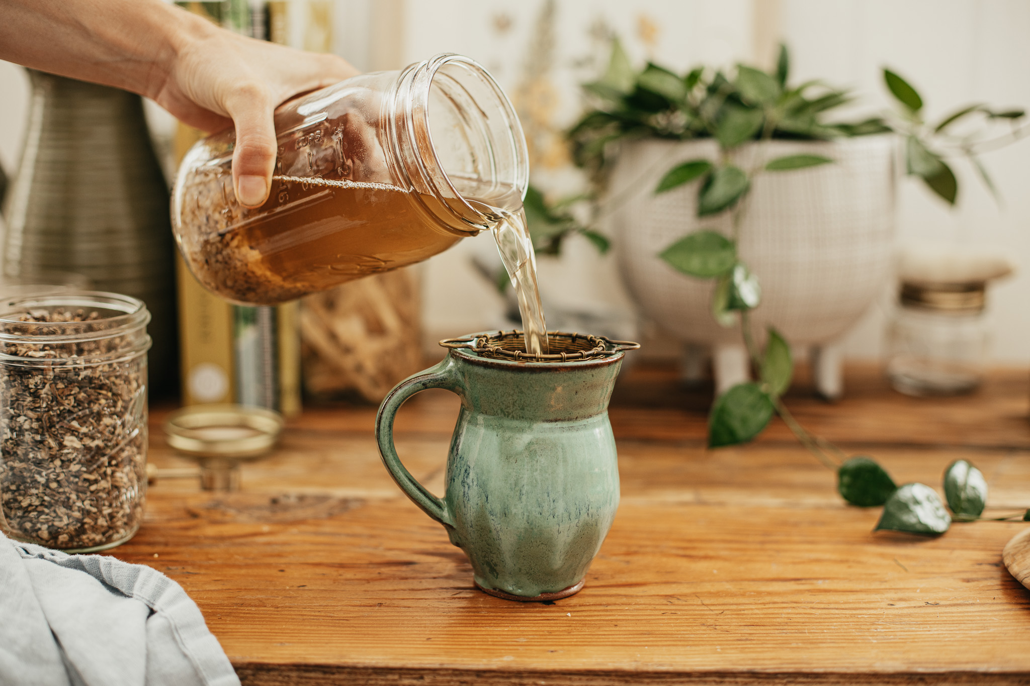 straining jar of root tonic into a mug