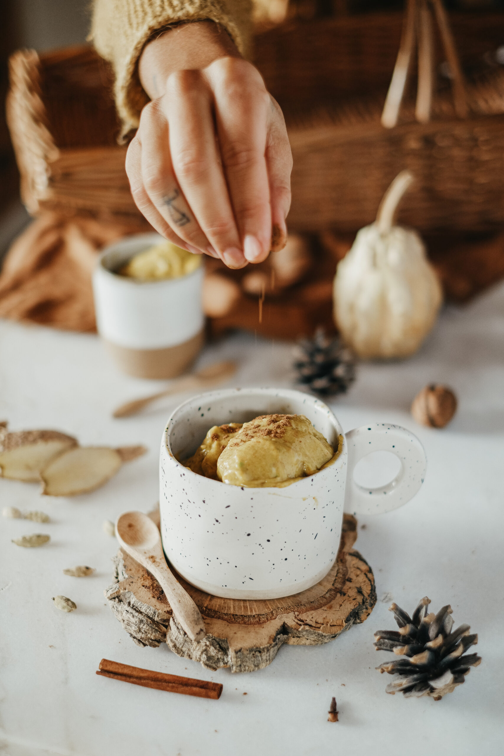 woman's hand sprinkling cinnamon on pumpkin spice nice cream