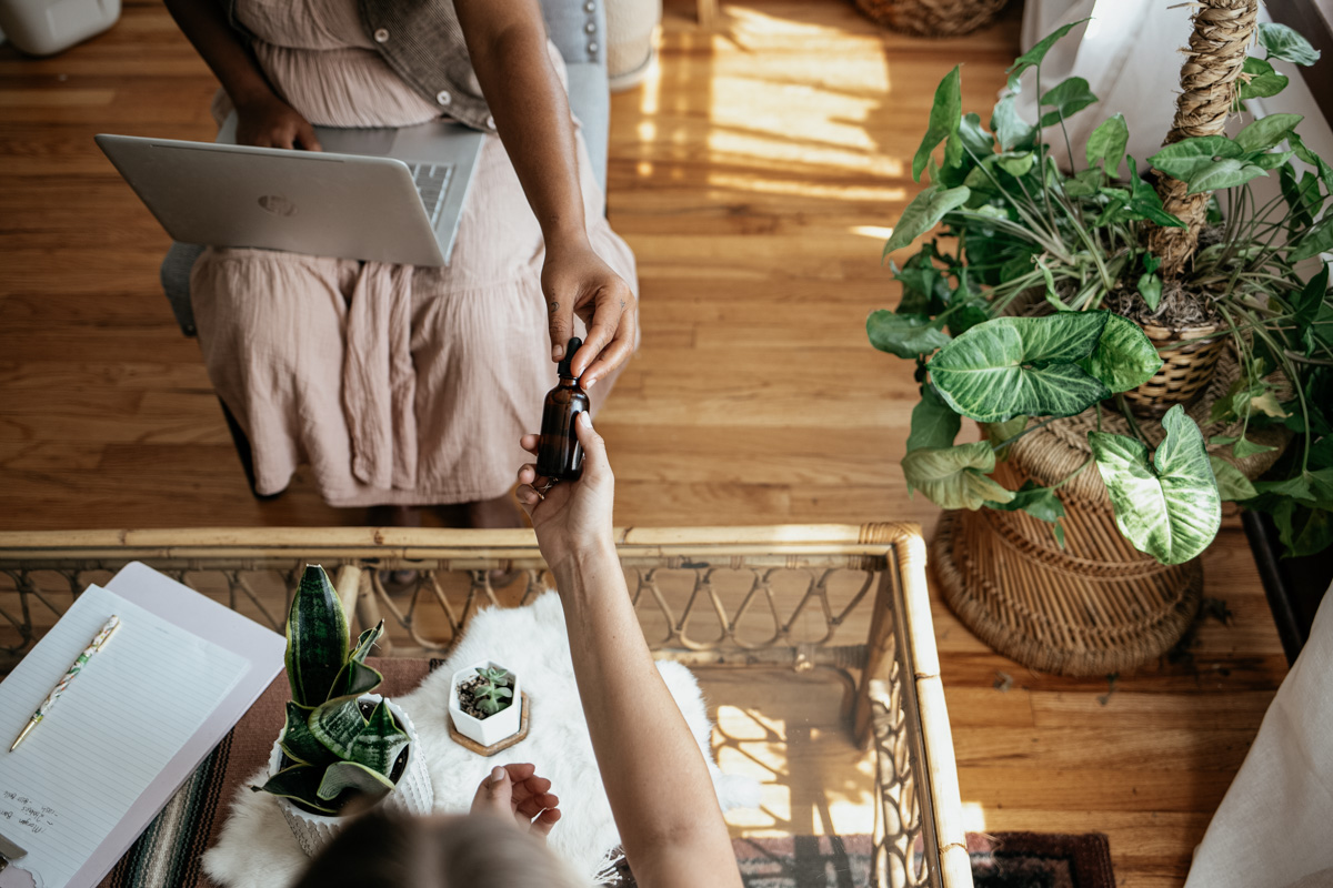 herbalist handing a tincture bottle across a table to a client