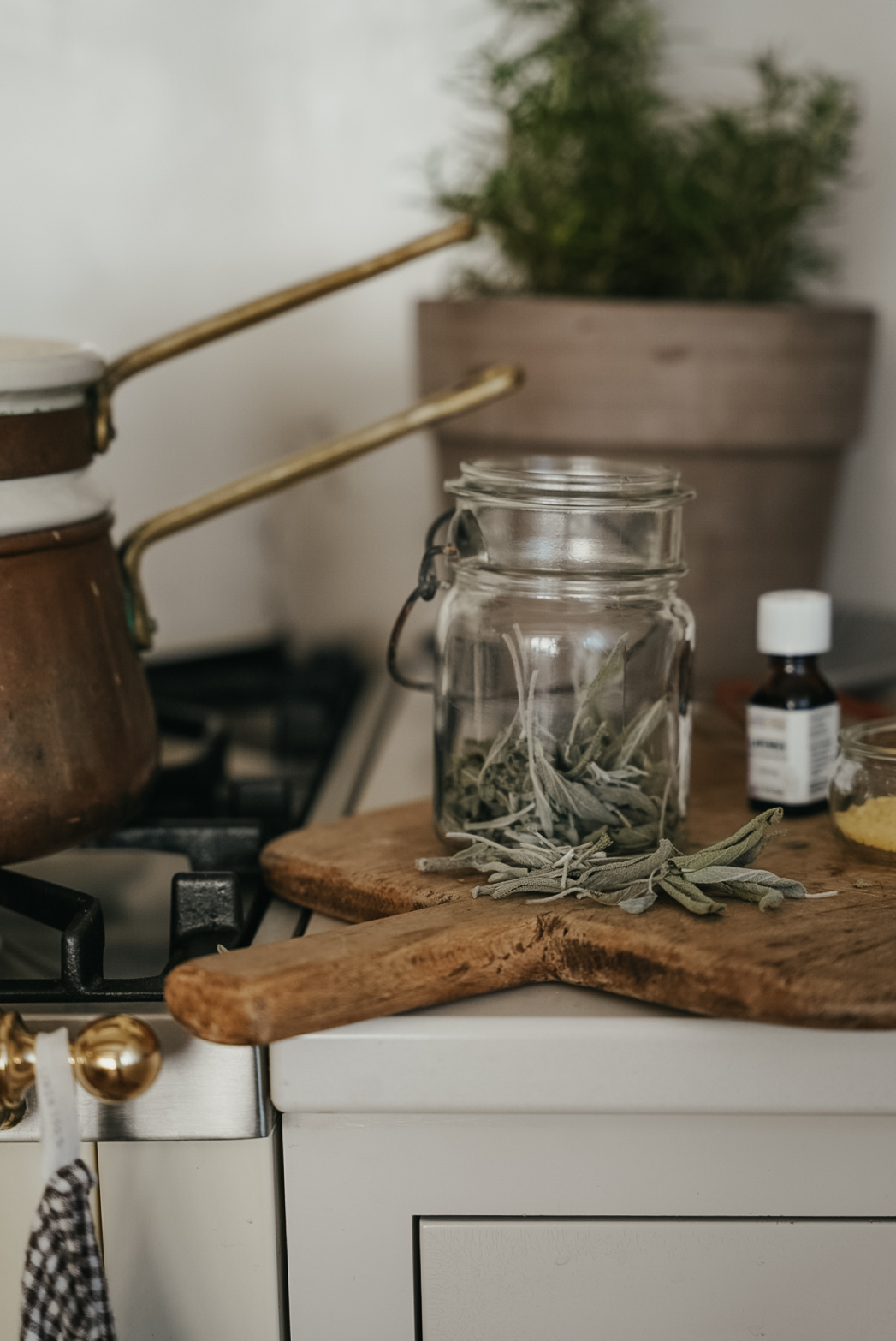 jar of sage on a wooden board with essential oils in the background