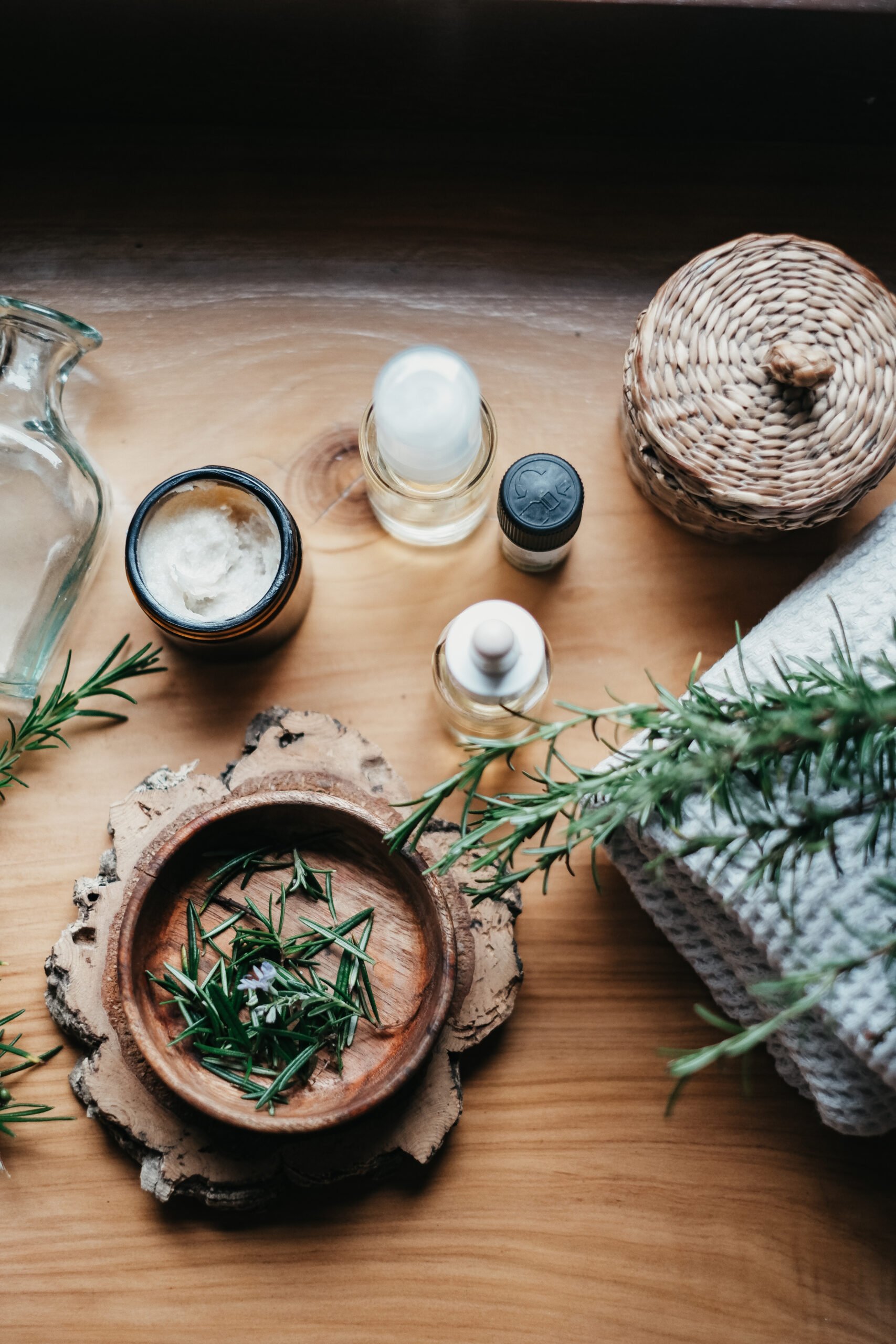 wood bowl of herbs with containers and herbs around it