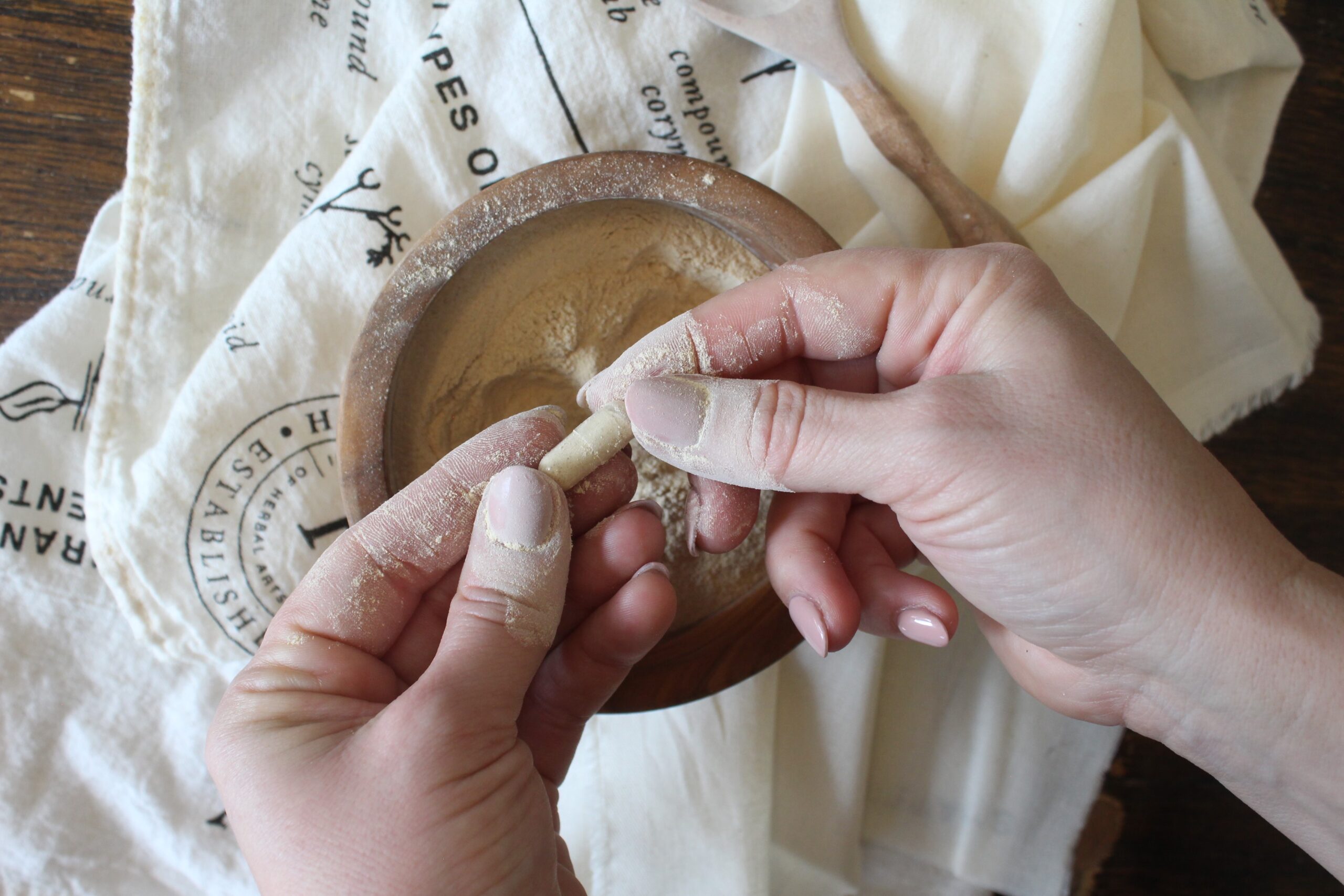 woman's hands filling capsules with powdered herb