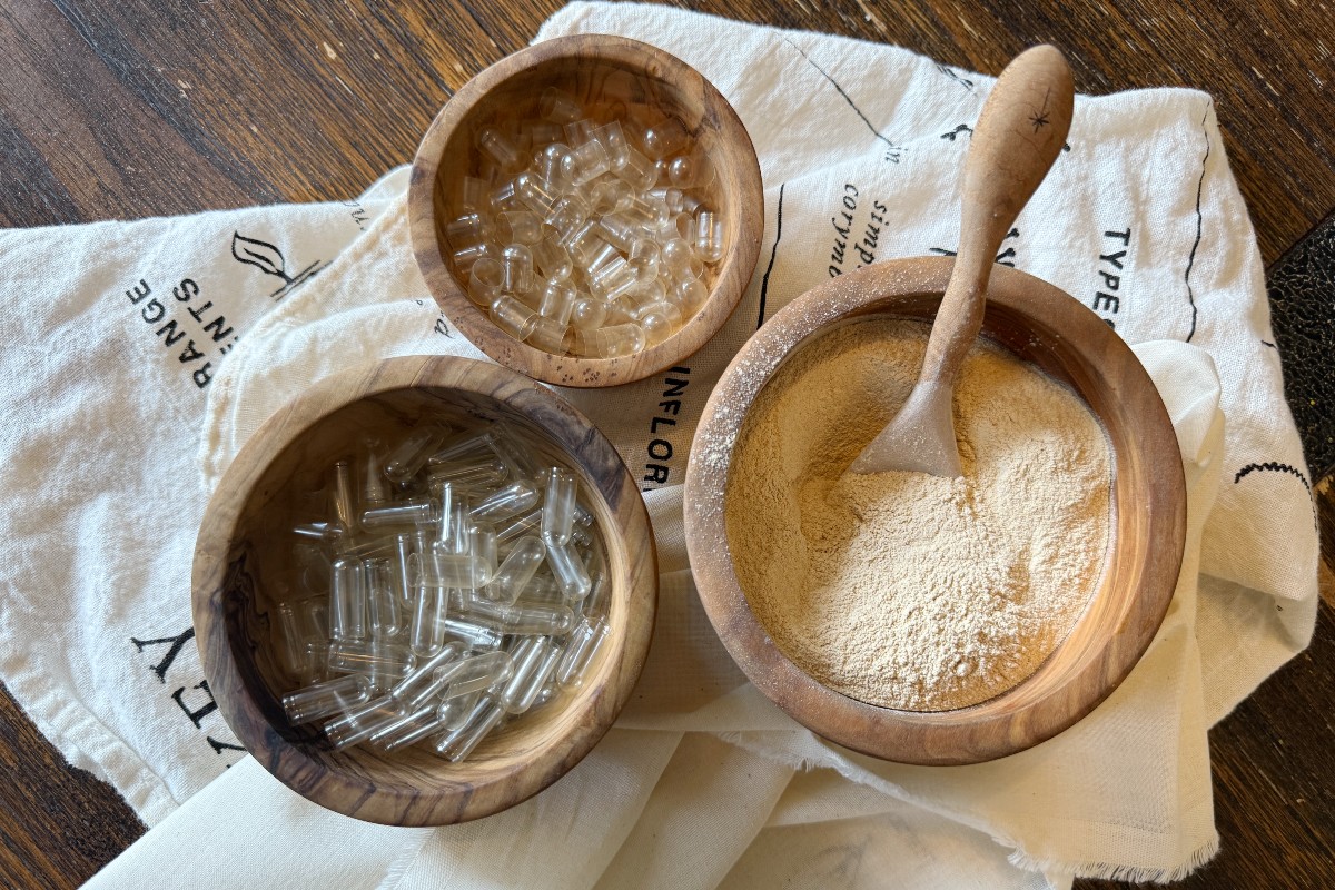 two bowls of empty capsules and a bowl of powdered herb