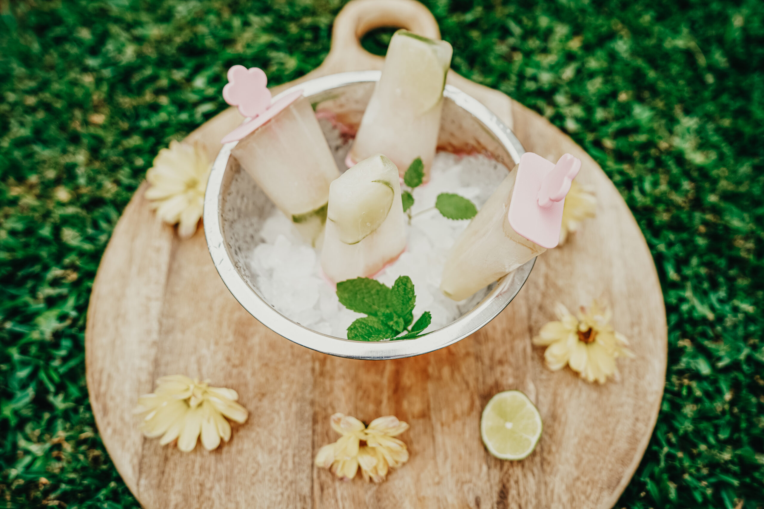 popsicles in a bowl of ice sitting on a round wooden board