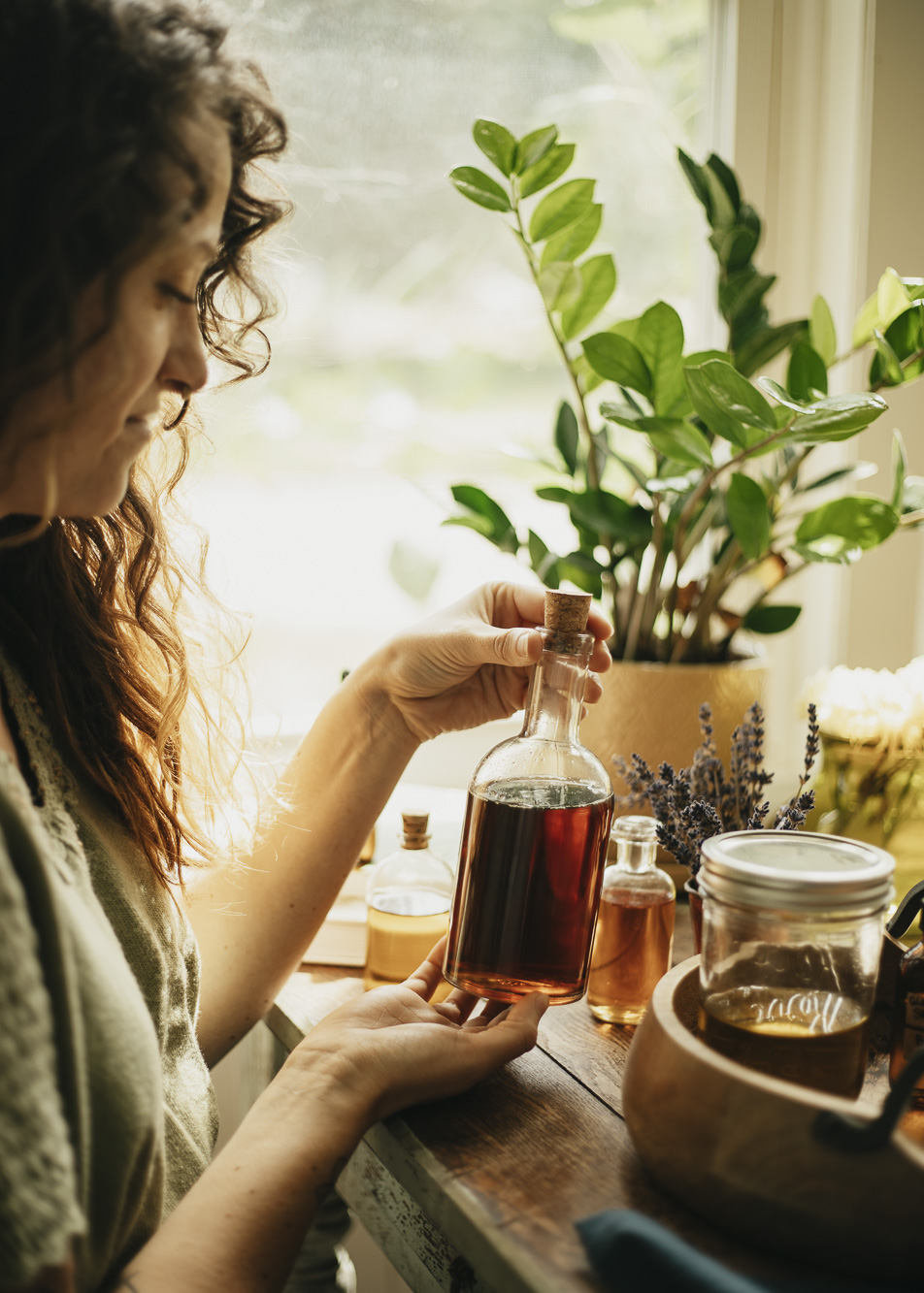 Woman holding bottle of infused oil - Herbal Academy's Herbal Oils Course