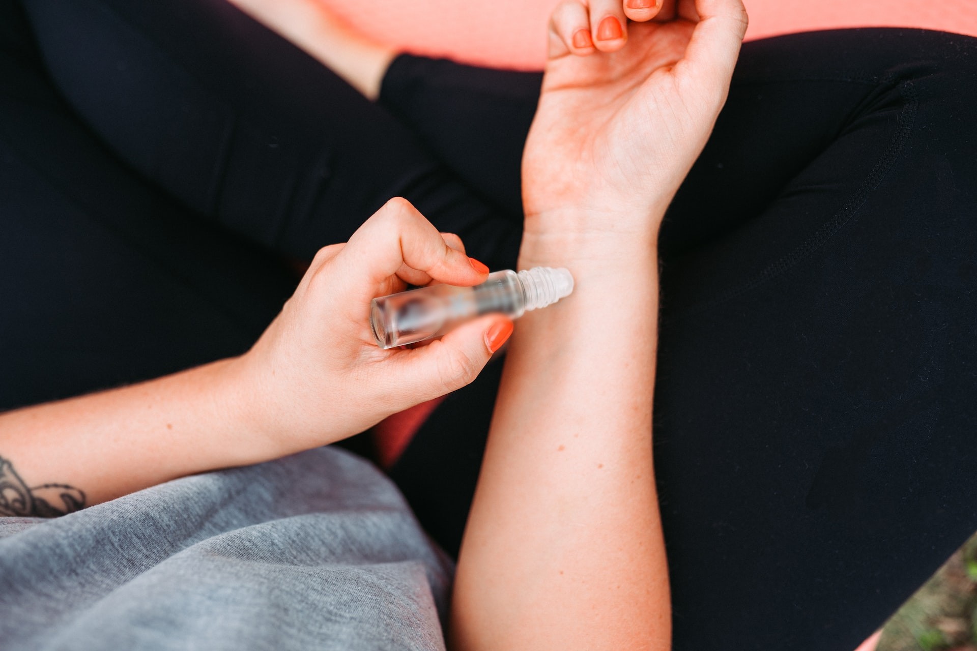 person rolling an essential oil roller bottle on the arm