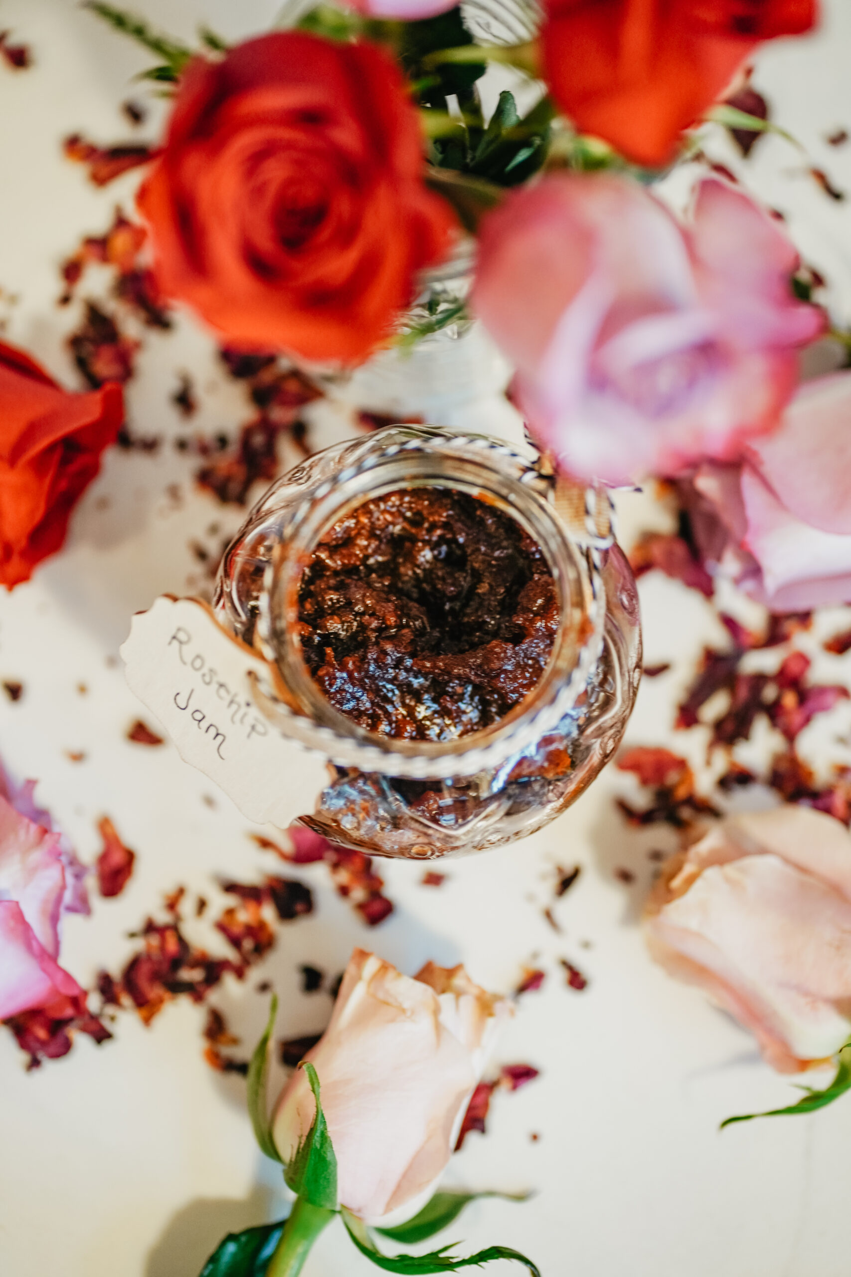 Discover this shimmering jam that perfectly captures the subtle beauty of the changing seasons: a Rosey Rose Hip Jam recipe. rose hip jam surrounded by roses