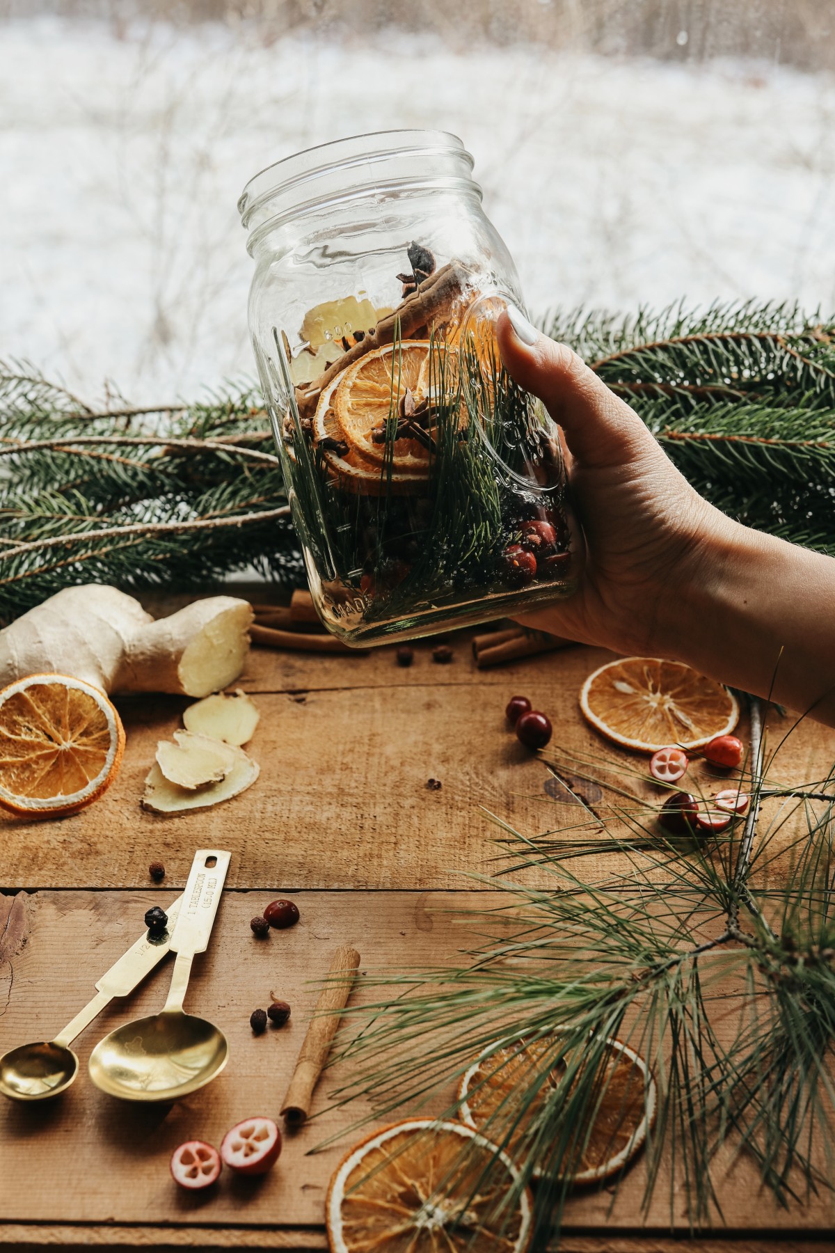 herbalist holding a jar of ingredients for the holiday tree cordial recipe