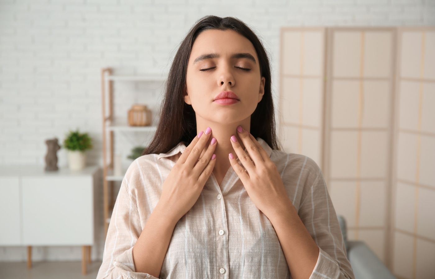 woman touching thyroid with eyes closed