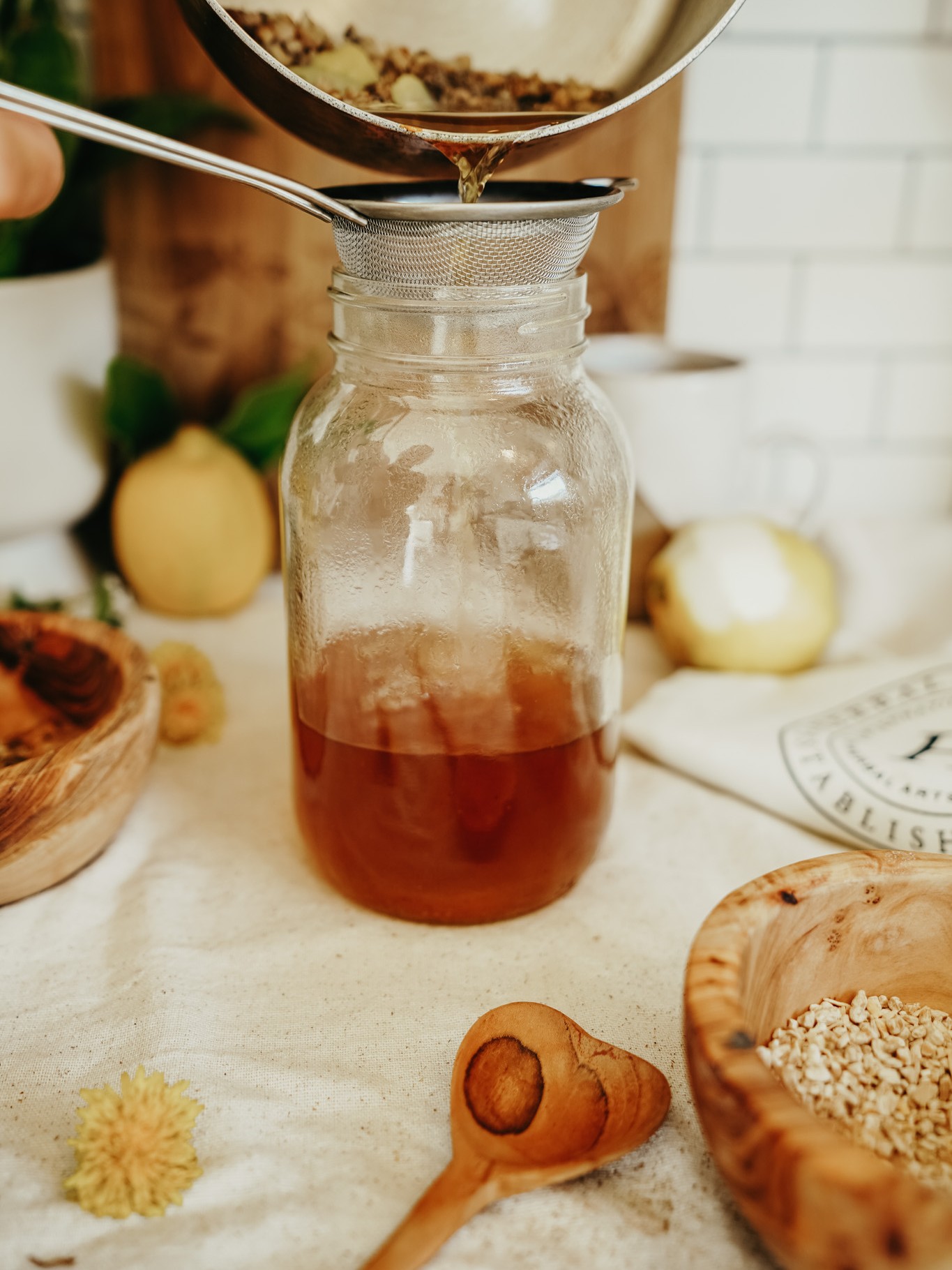 An herbal tea being strained into a glass jar, representing the types of recipes covered in Herbal Academy's Holistic Approach for Tick-Borne Diseases Course. 