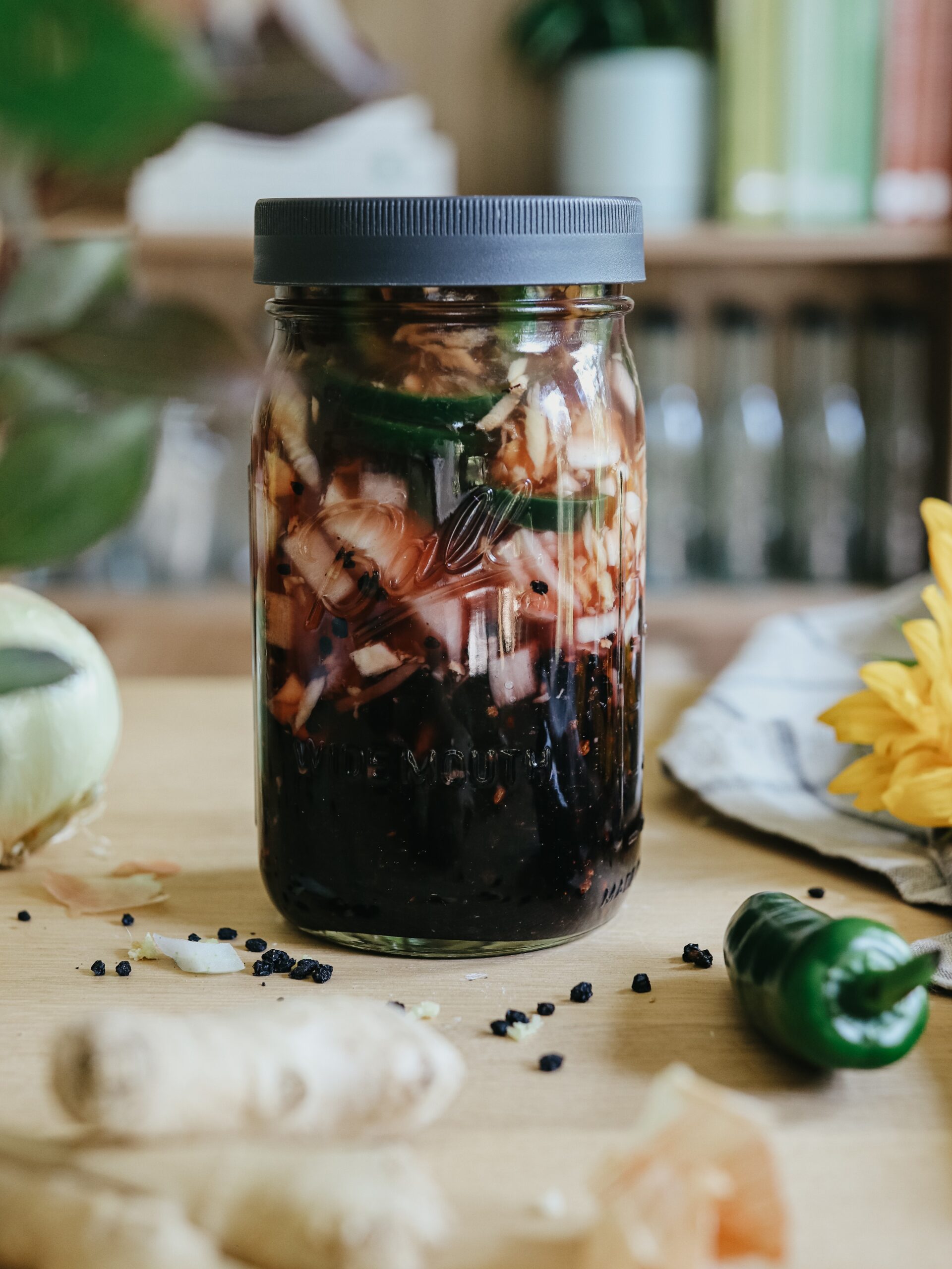 A glass jar on a table, filled with herbs and a dark-red liquid. Representing the type of herbal preparations covered in Herbal Academy's Holistic Approach for Tick-Borne Diseases Course. 